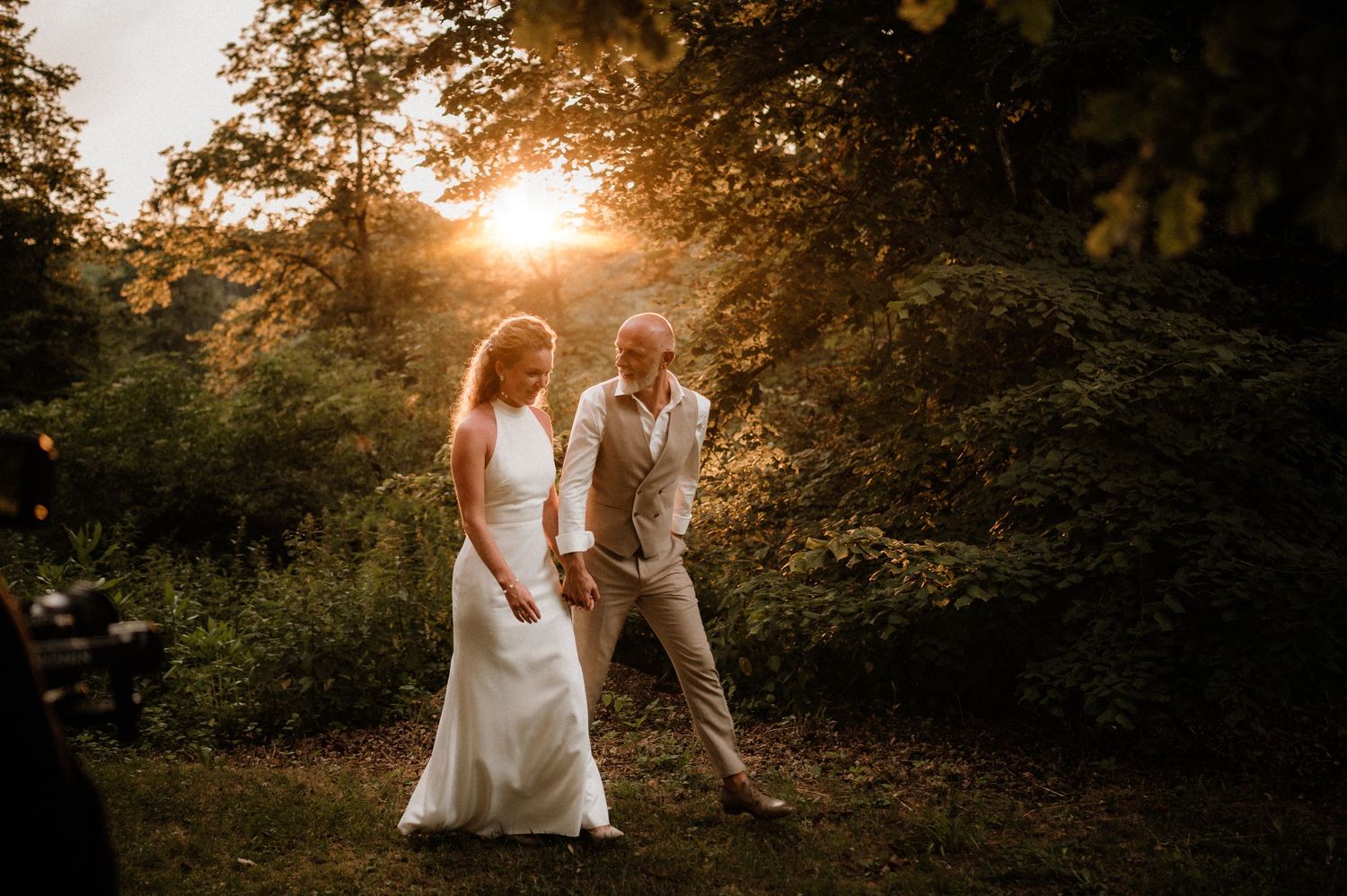 A romantic sunset silhouettes a couple during their outdoor wedding photoshoot.