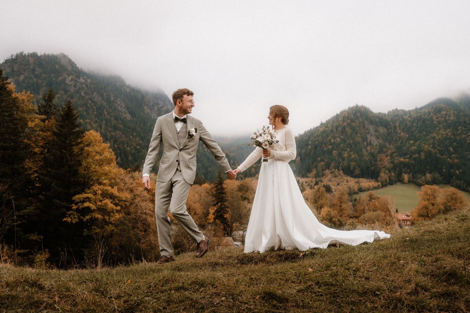 Herbsthochzeitsfotografie-Session auf einer malerischen Bergwiese mit goldenem Licht. Von Dama Fotografie Bad Tölz