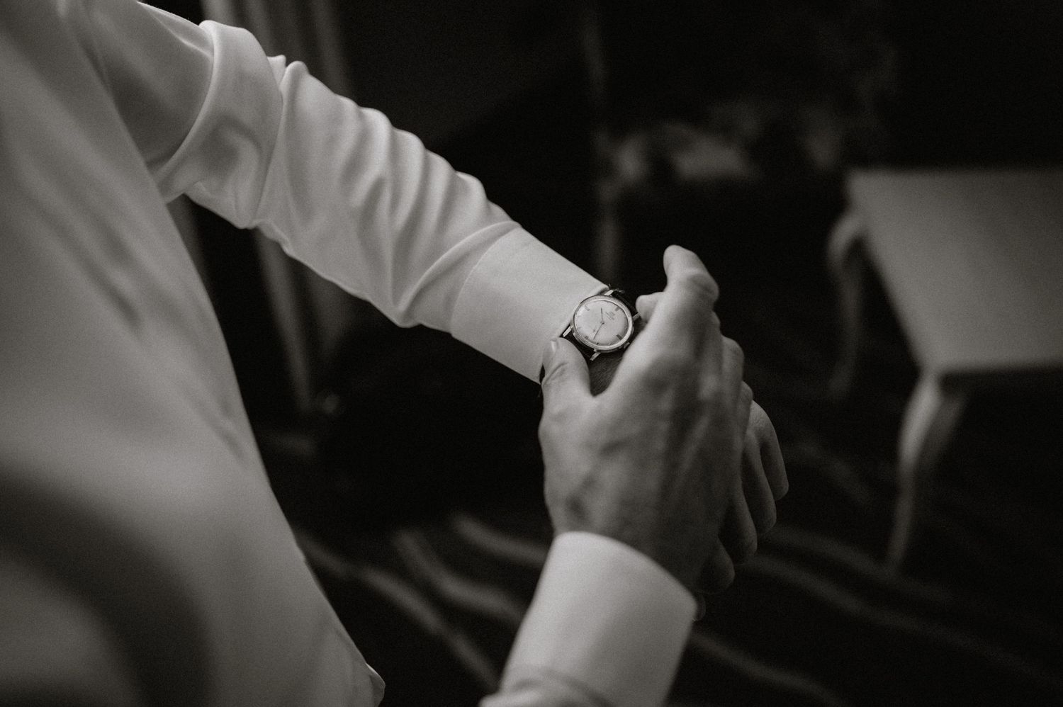 Black and white photo of hands adjusting formal attire in preparation.