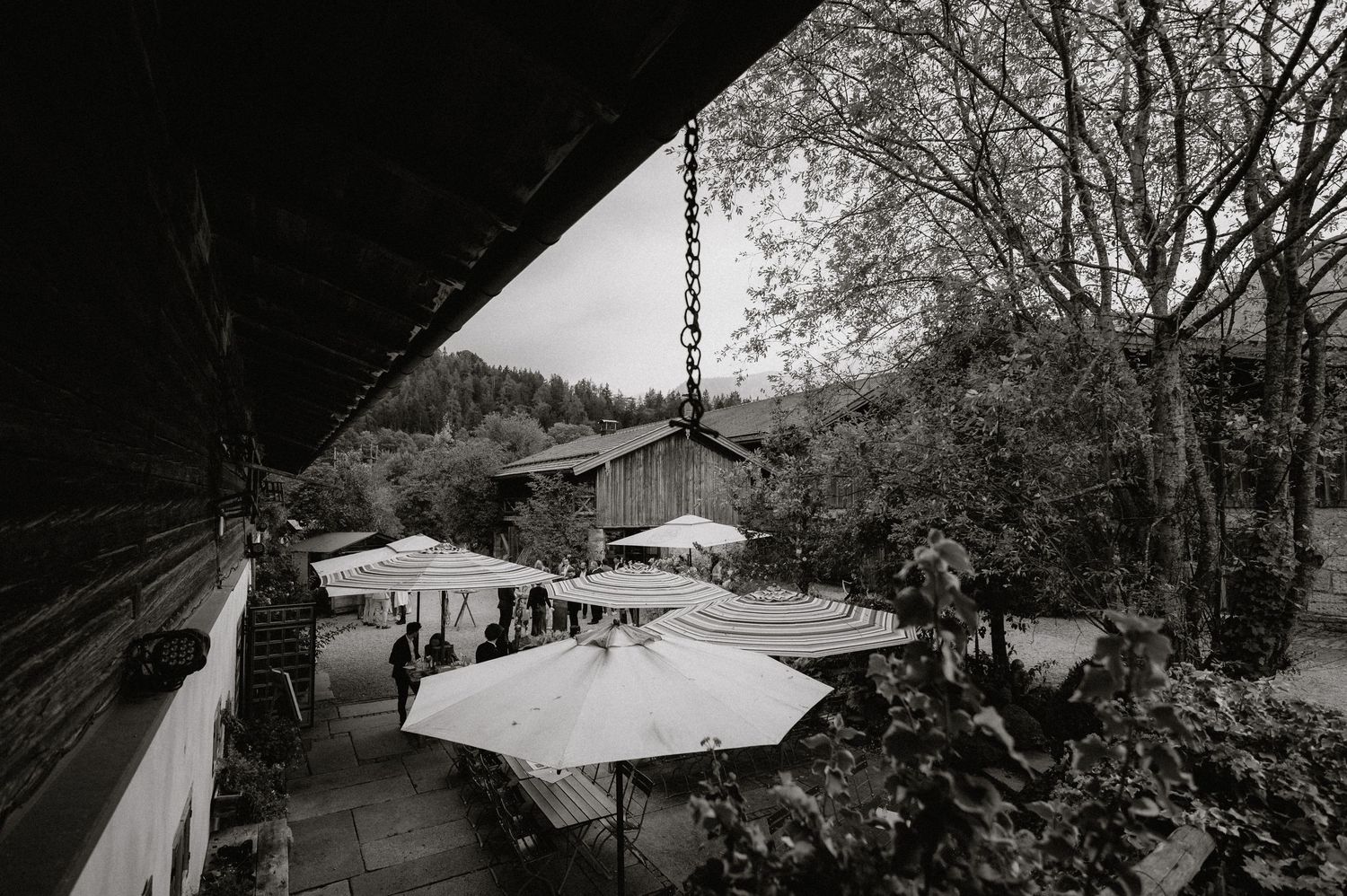 Panoramic black and white landscape view of rural buildings and trees.