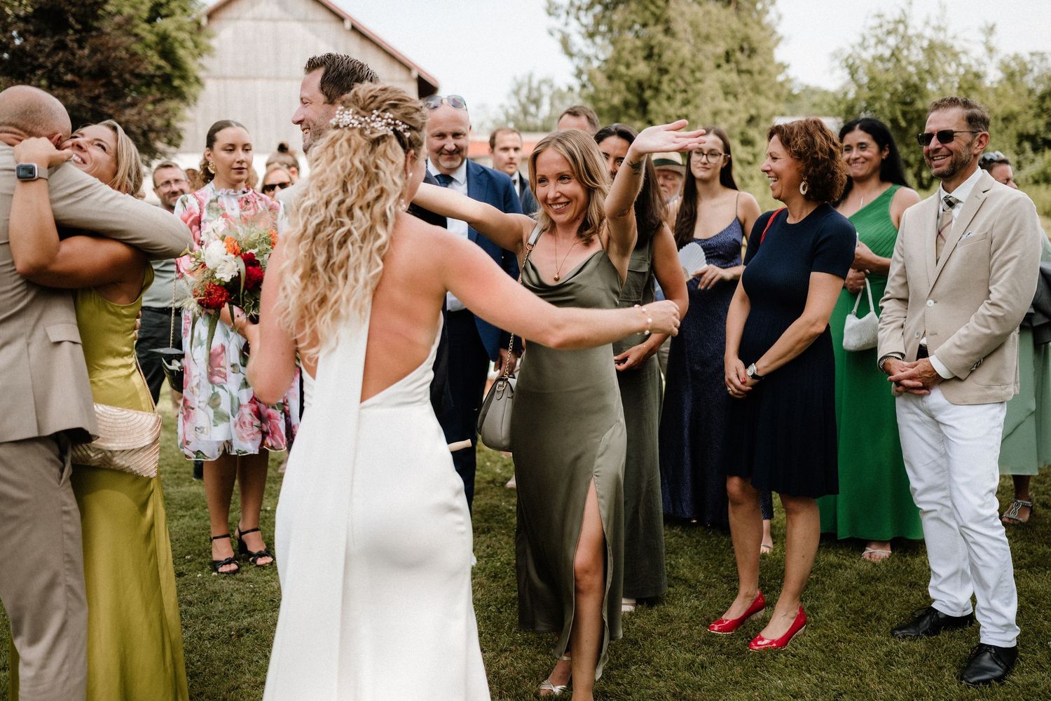 Wedding party and guests mingling outdoors during a daytime celebration.