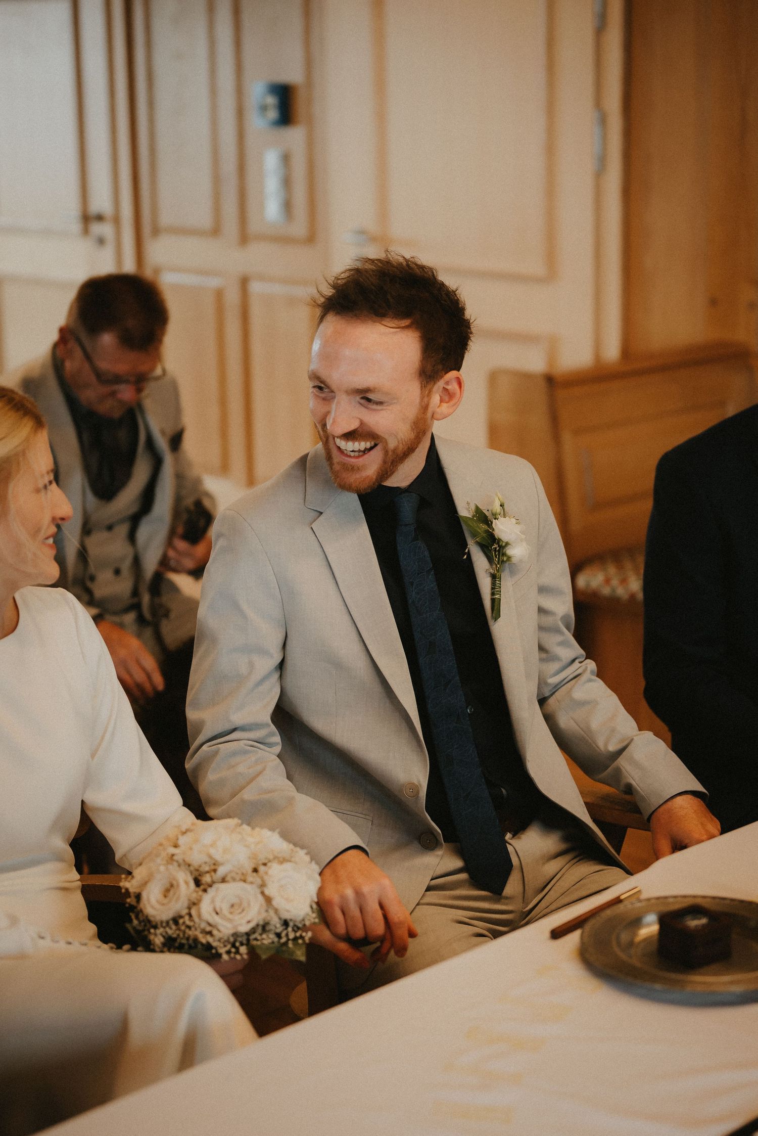 Wedding guests in formal attire sharing laughs at an elegant indoor reception.