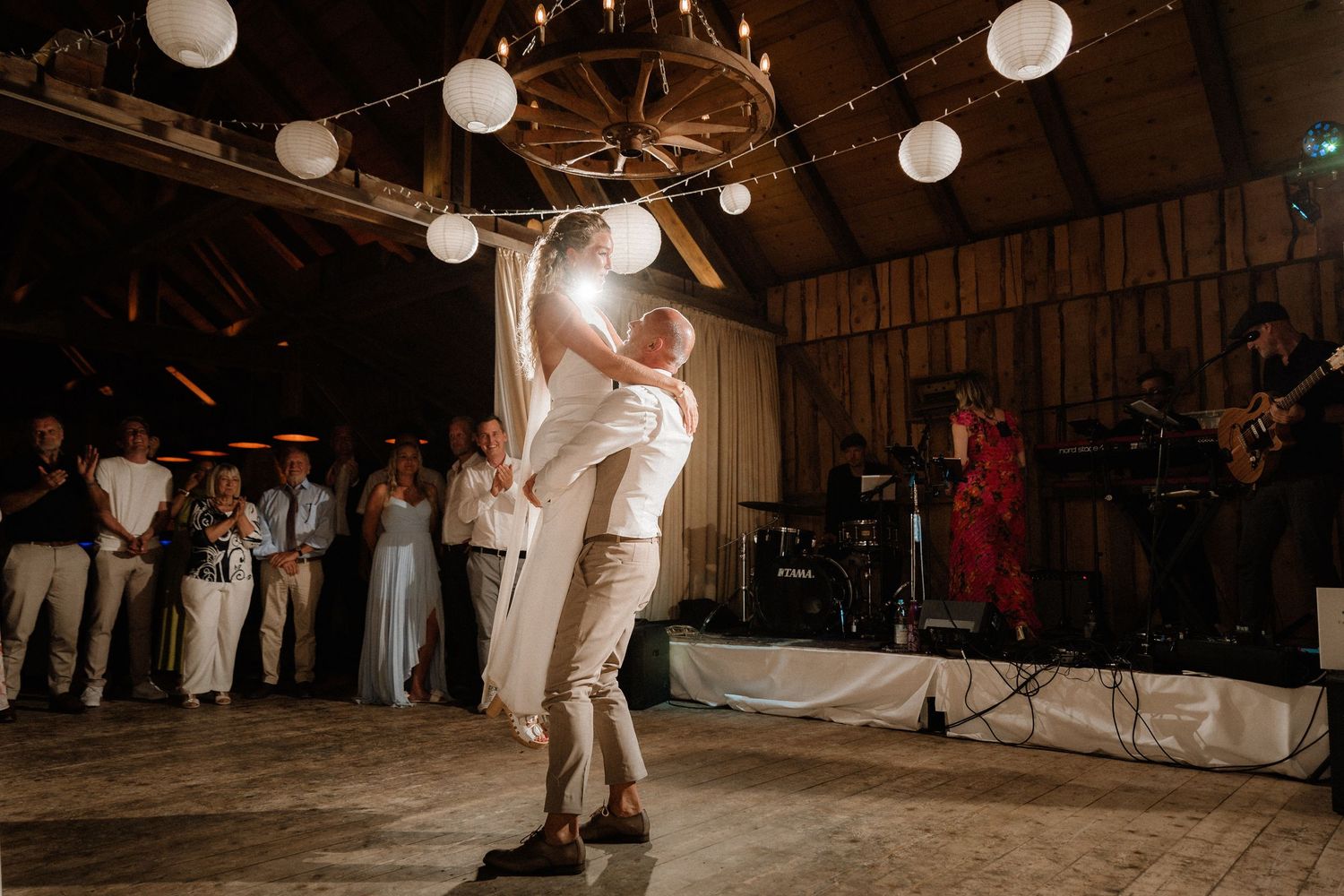 Dancing couples celebrate on a wooden dance floor under glowing paper lanterns.