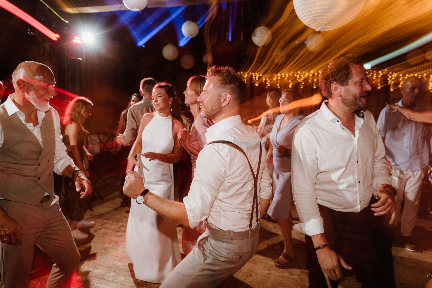 Wedding reception dance floor scene with white paper lanterns and red accent lighting.