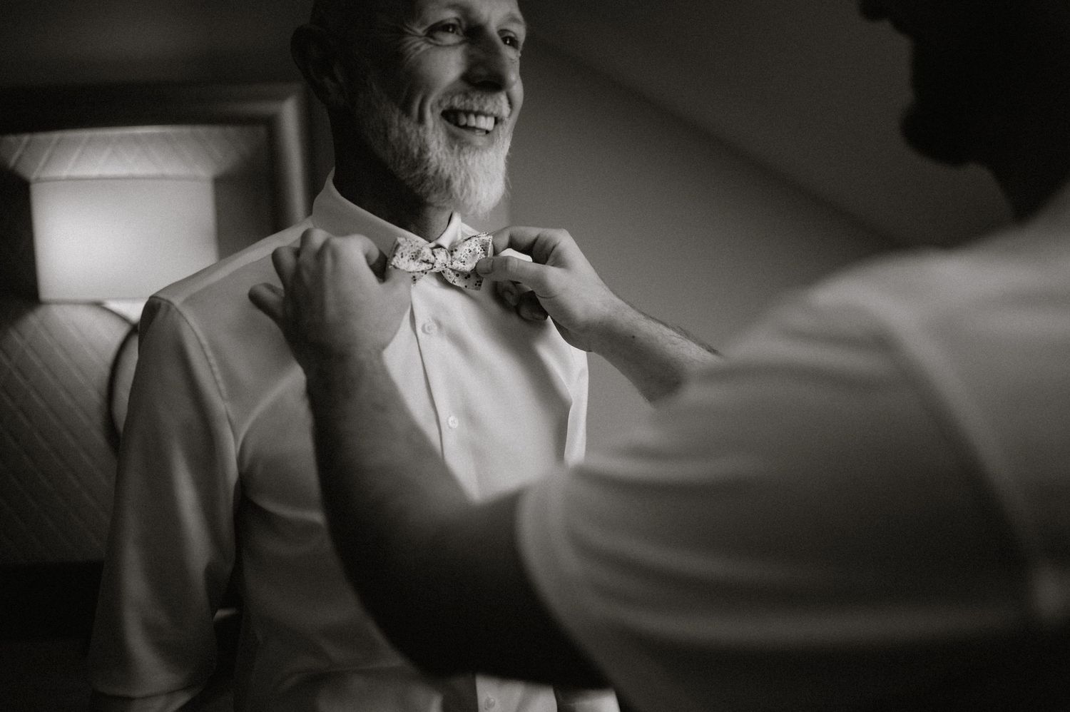 Black and white candid moment captured through window light.