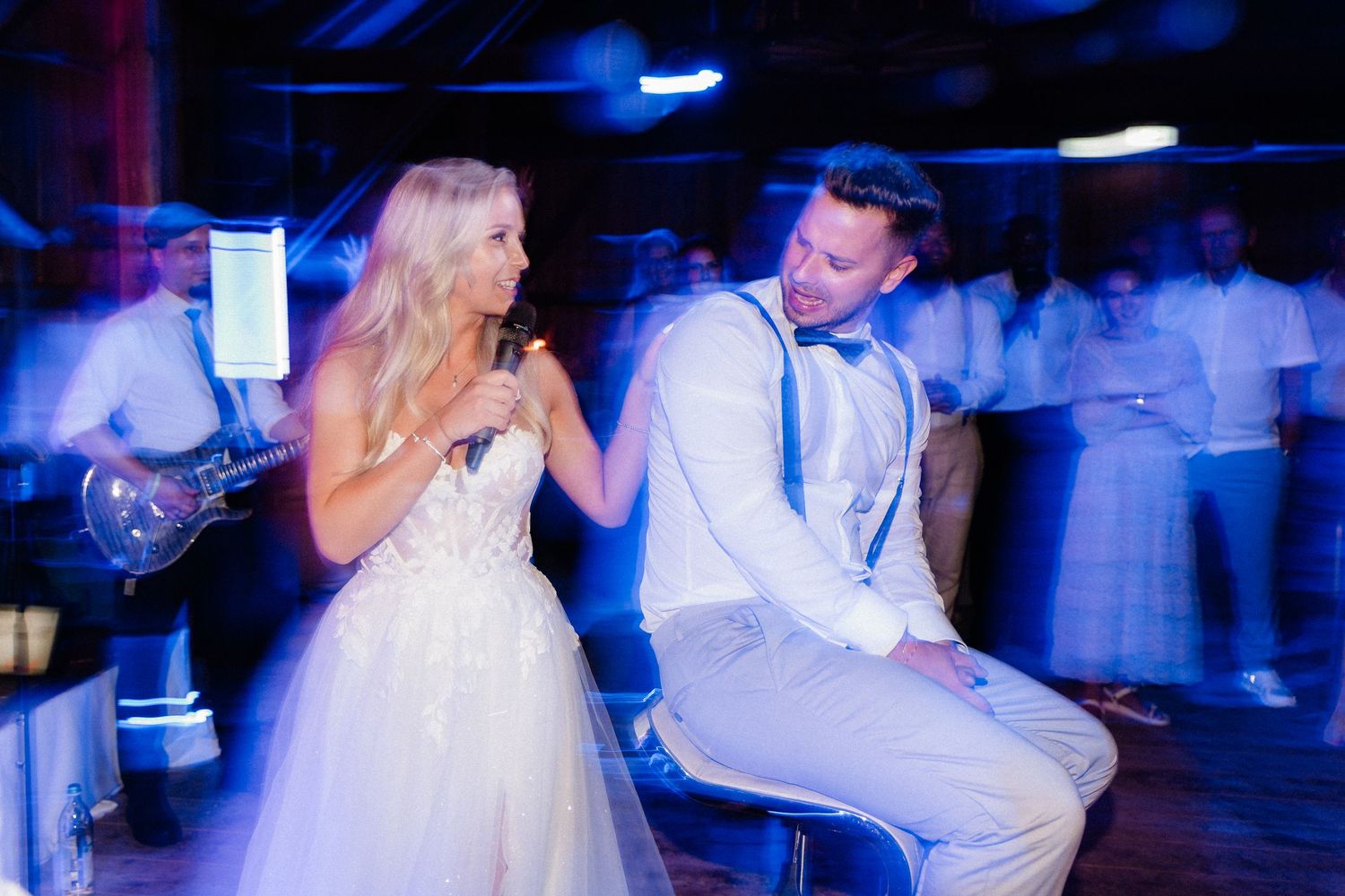 Couples dancing at a wedding reception with dramatic blue lighting effects.