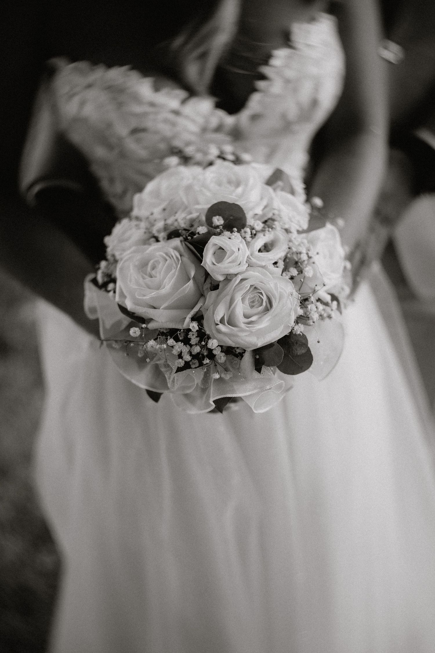 Eleganter Brautstrauß aus weißen Rosen und zarten Blumen vor einem Hochzeitskleid. Von Dama Fotografie Bad Tölz