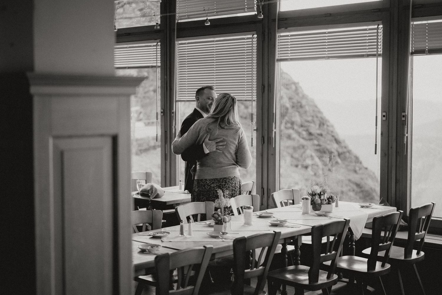 Romantic silhouette of a couple by a window in a mountain restaurant with scenic views.