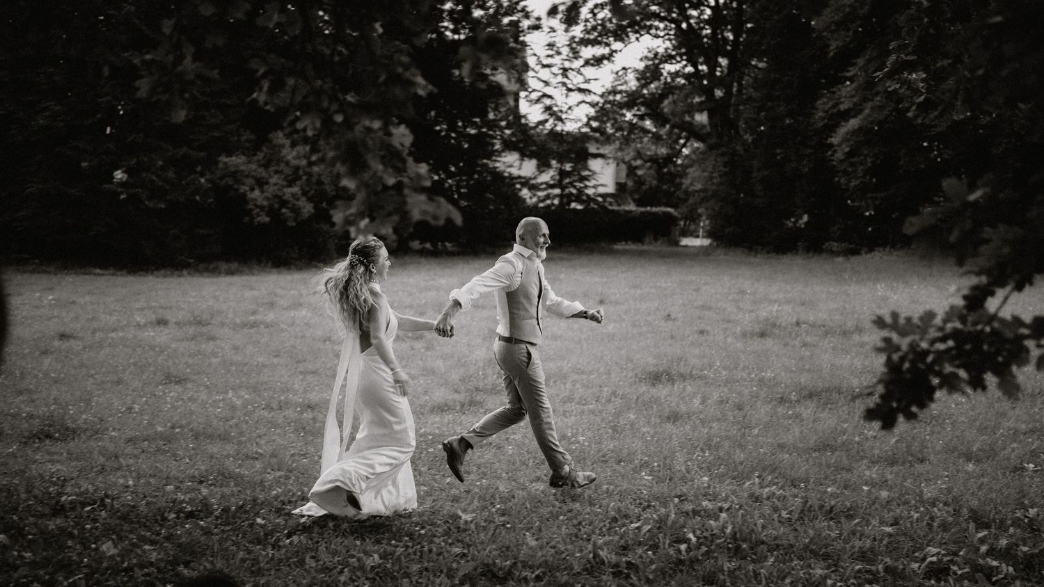 A couple dancing and twirling in a sunlit meadow surrounded by nature.