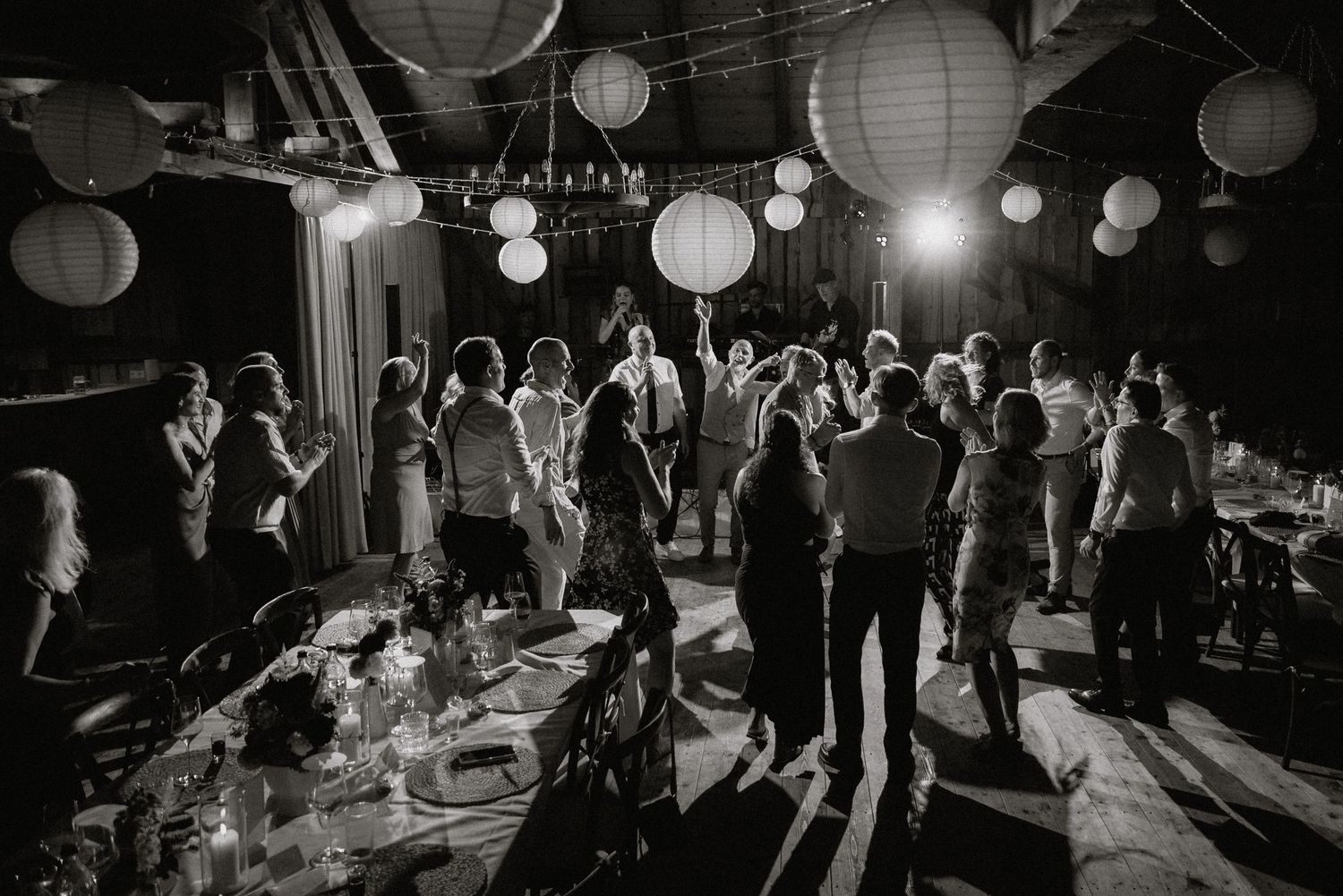 Wide shot of a wedding reception venue with paper lanterns and guests dancing.