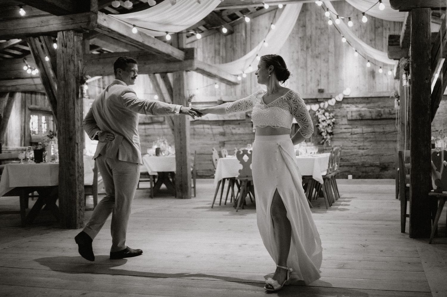 Couple dancing in a rustic barn venue decorated with string lights.