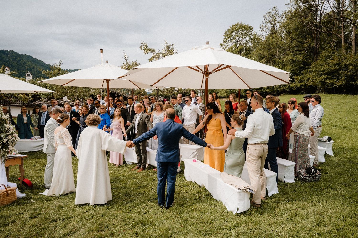 A scenic outdoor wedding reception with white umbrellas and mountain views in the background.