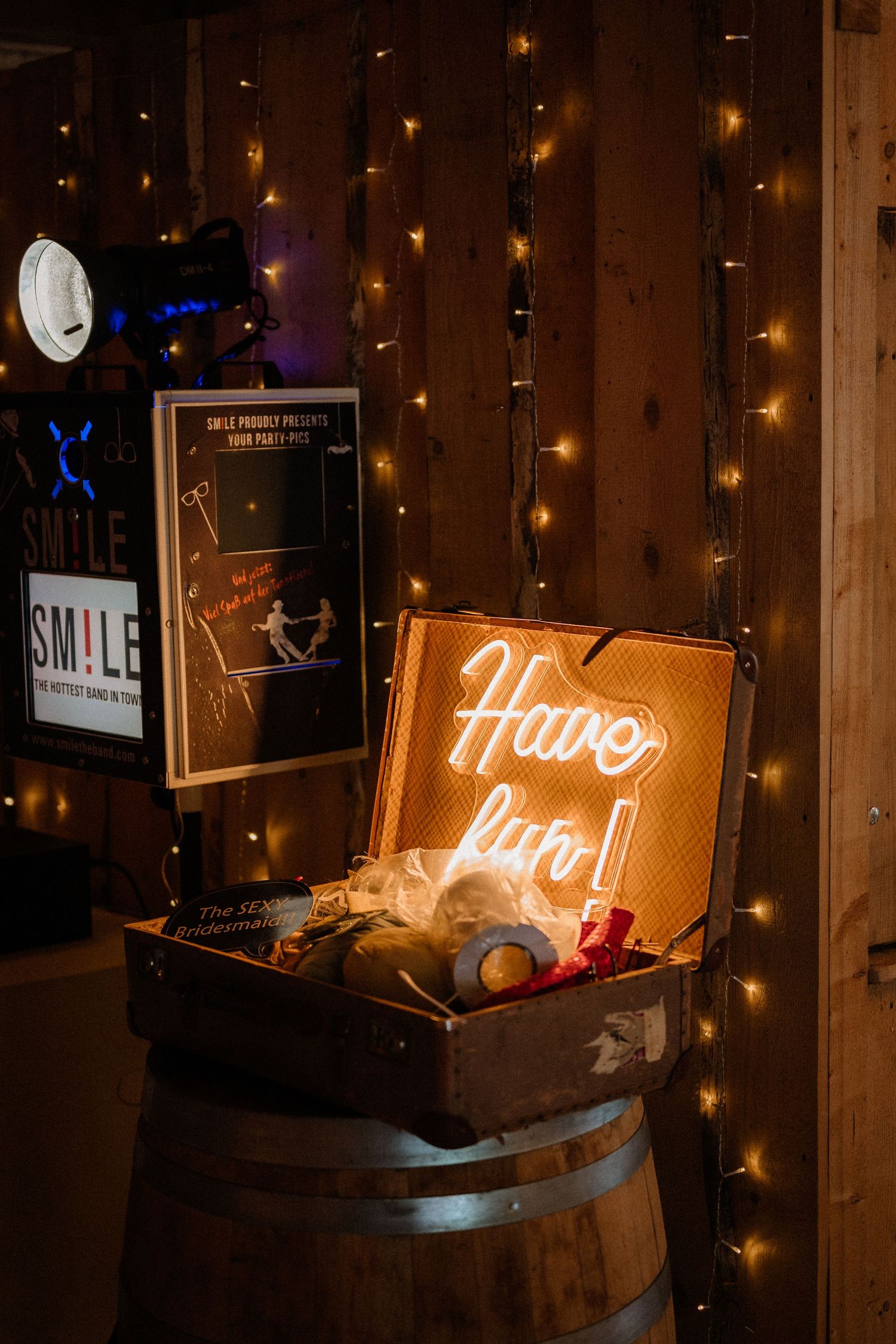 Vintage suitcase display with neon signs and string lights at a wedding reception.