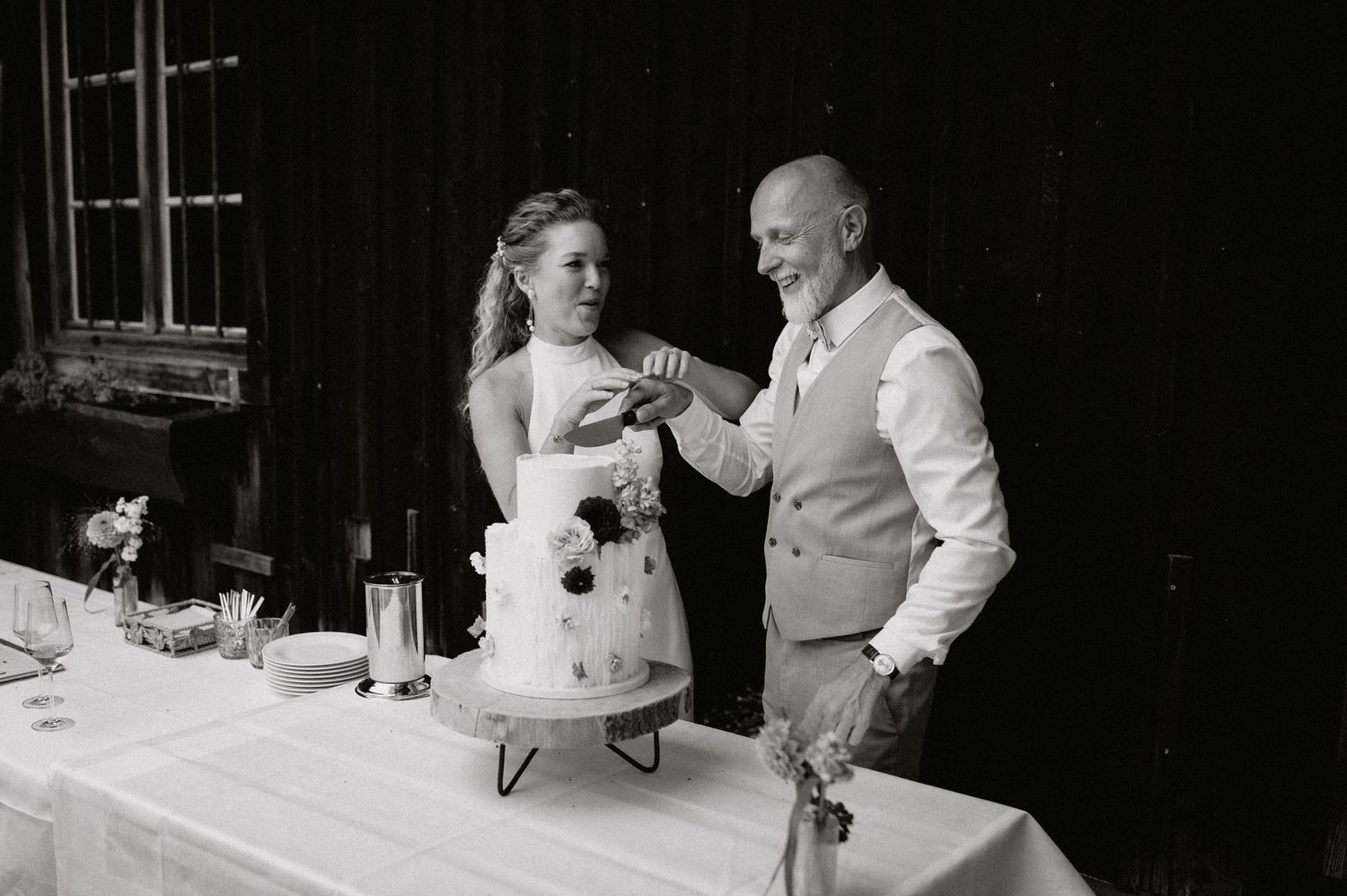 A couple shares a joyful moment during their wedding reception at a rustic indoor venue.