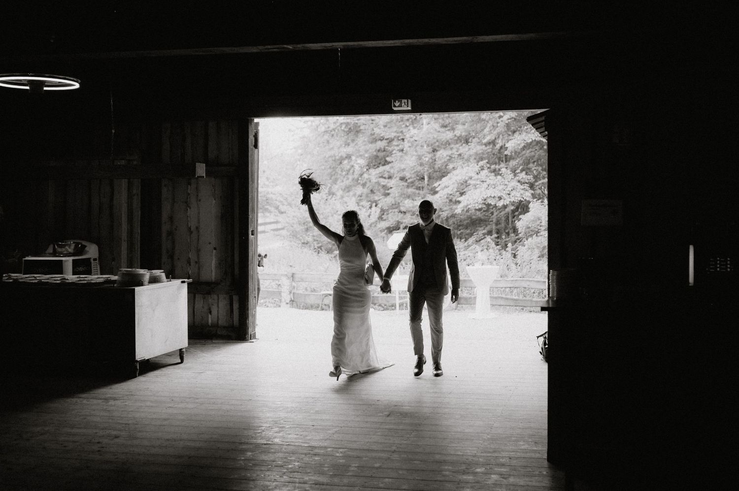 Silhouettes of people walking through a dark barn doorway creating dramatic lighting effects.