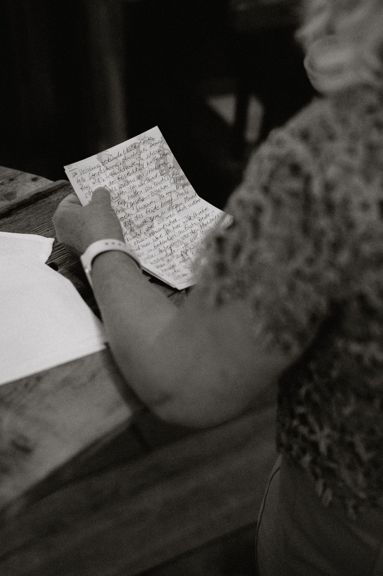 Close-up black and white shot of hands writing on paper.