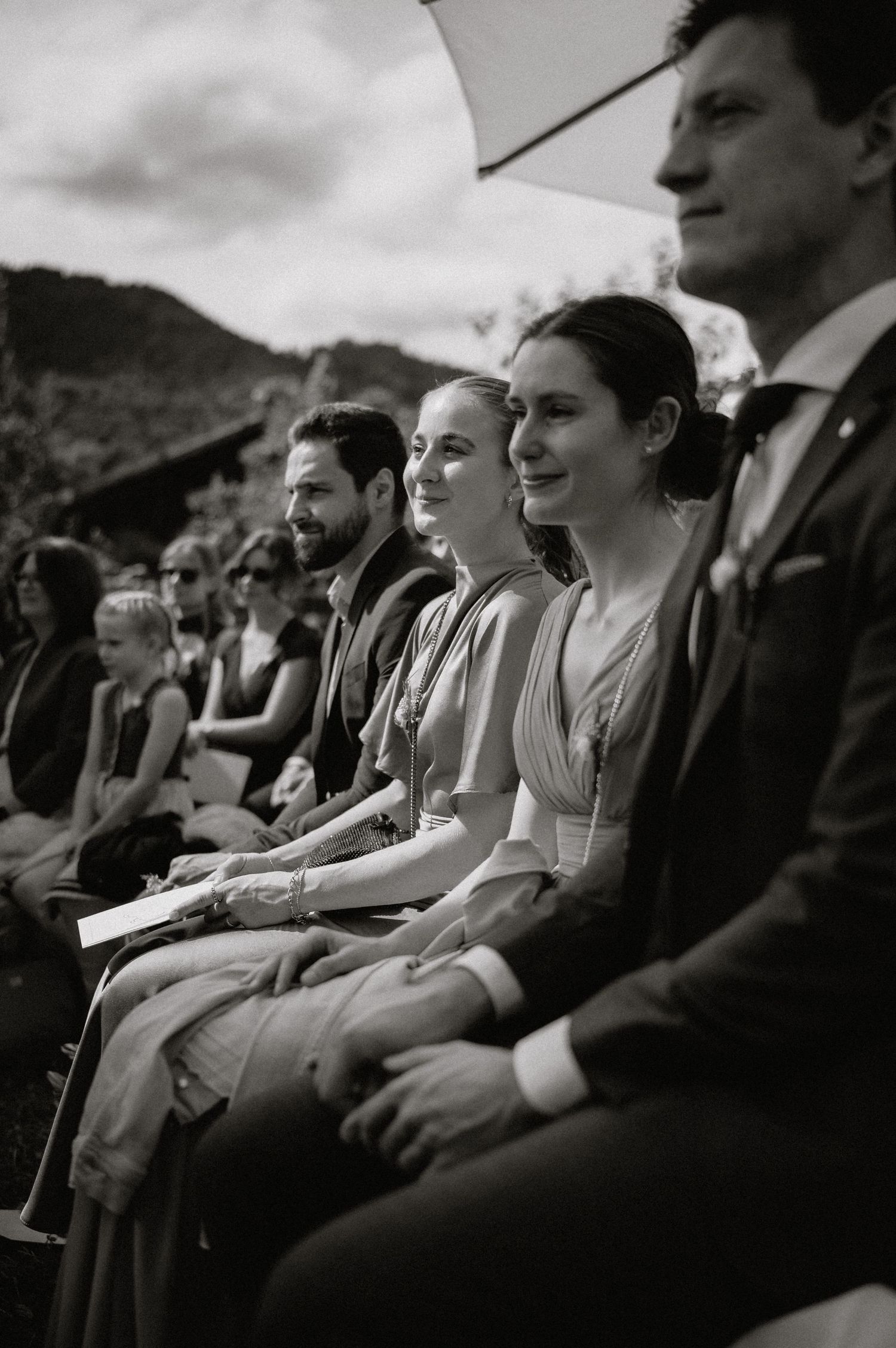 Wedding guests seated outdoors at a mountain ceremony in black and white.