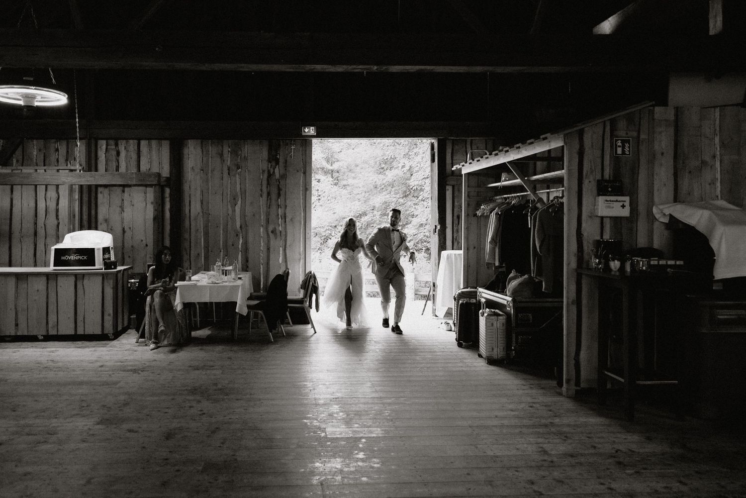 Dark silhouettes move across a dimly lit rustic barn interior.