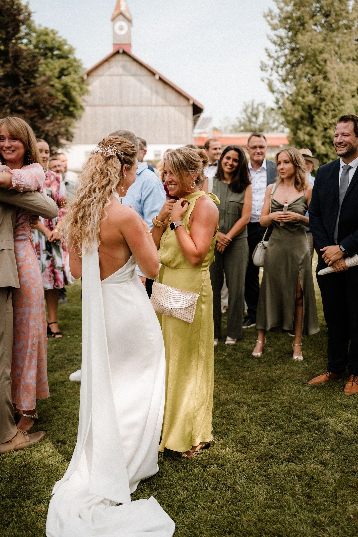 Wedding celebration on a grassy lawn with guests in colorful dresses and formal attire.