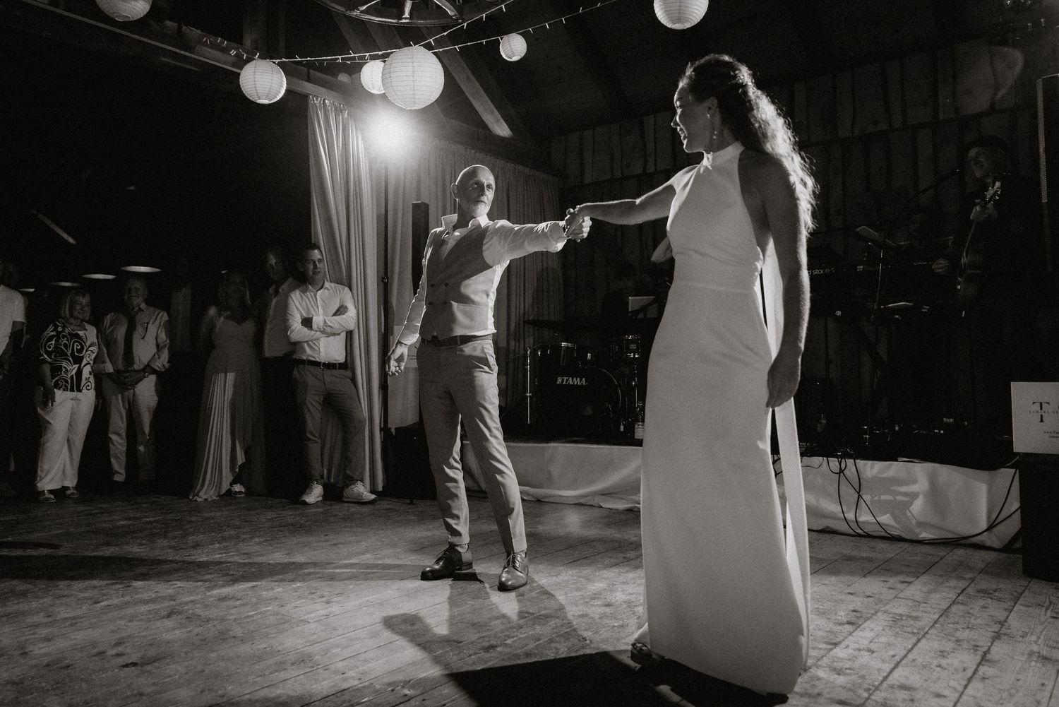 A romantic first dance under paper lanterns in a rustic barn venue.