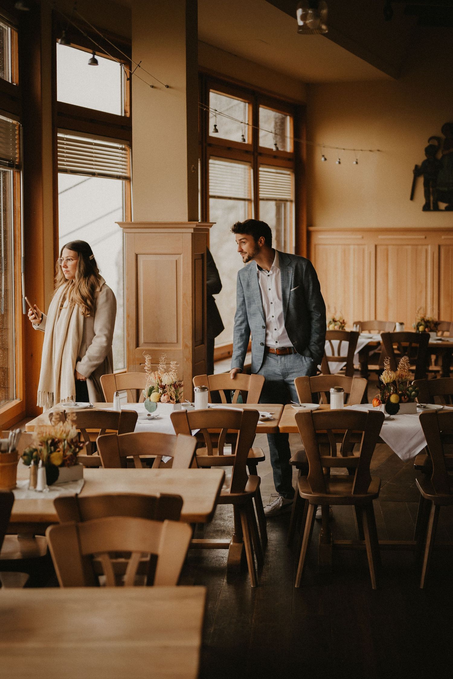 Warm-toned interior of a rustic restaurant dining room with wooden furniture.