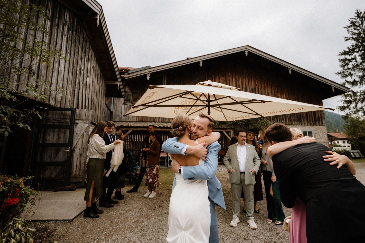 Newlyweds share a dance under white umbrellas outside a rustic barn venue.