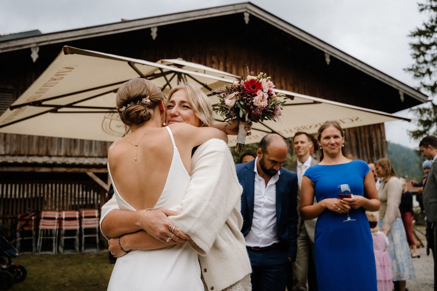Festive wedding celebration with guests outside rustic wooden barn.