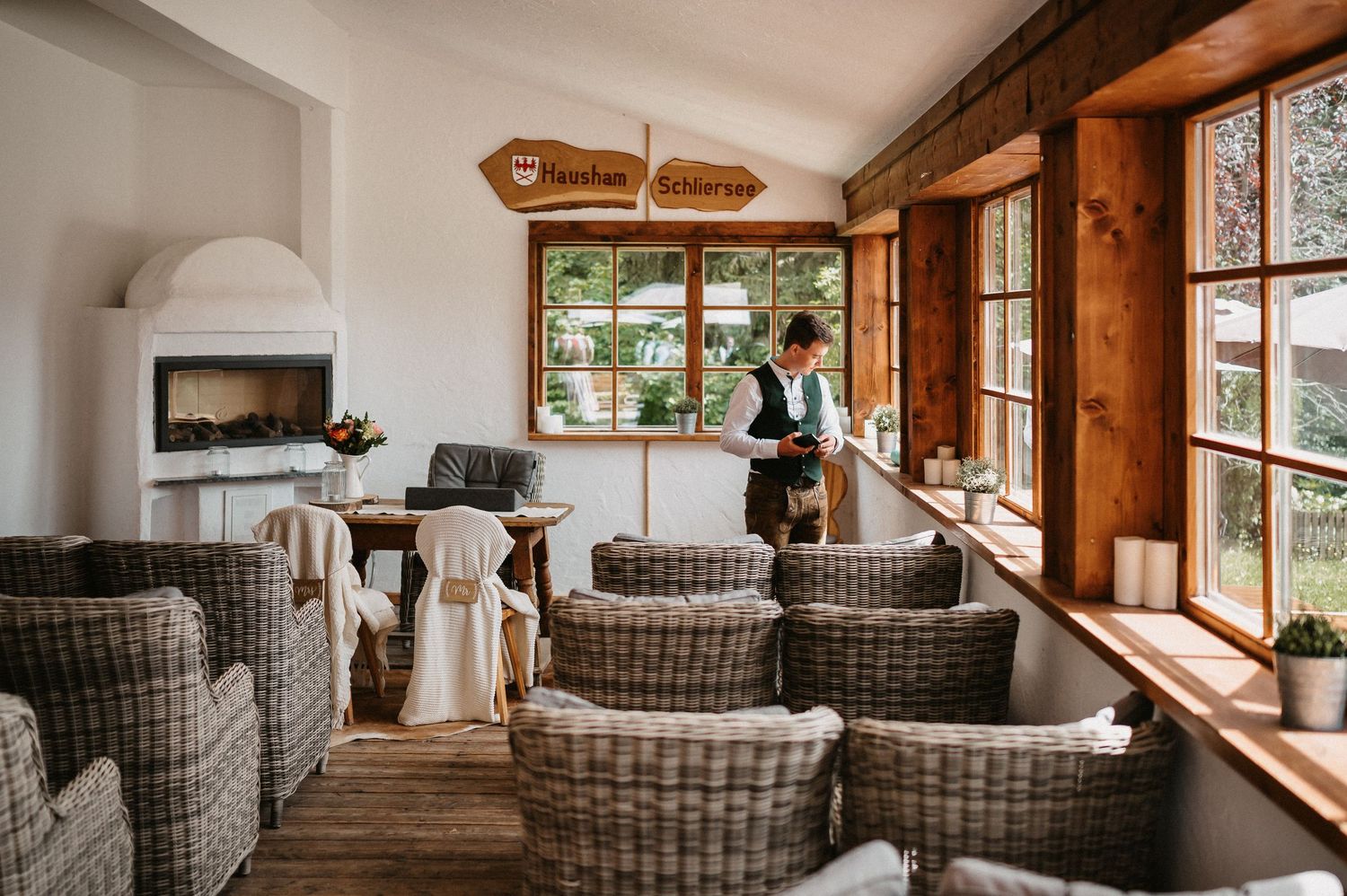 A cozy seating area in a rustic lodge with wicker chairs and large windows overlooking a scenic outdoor view.