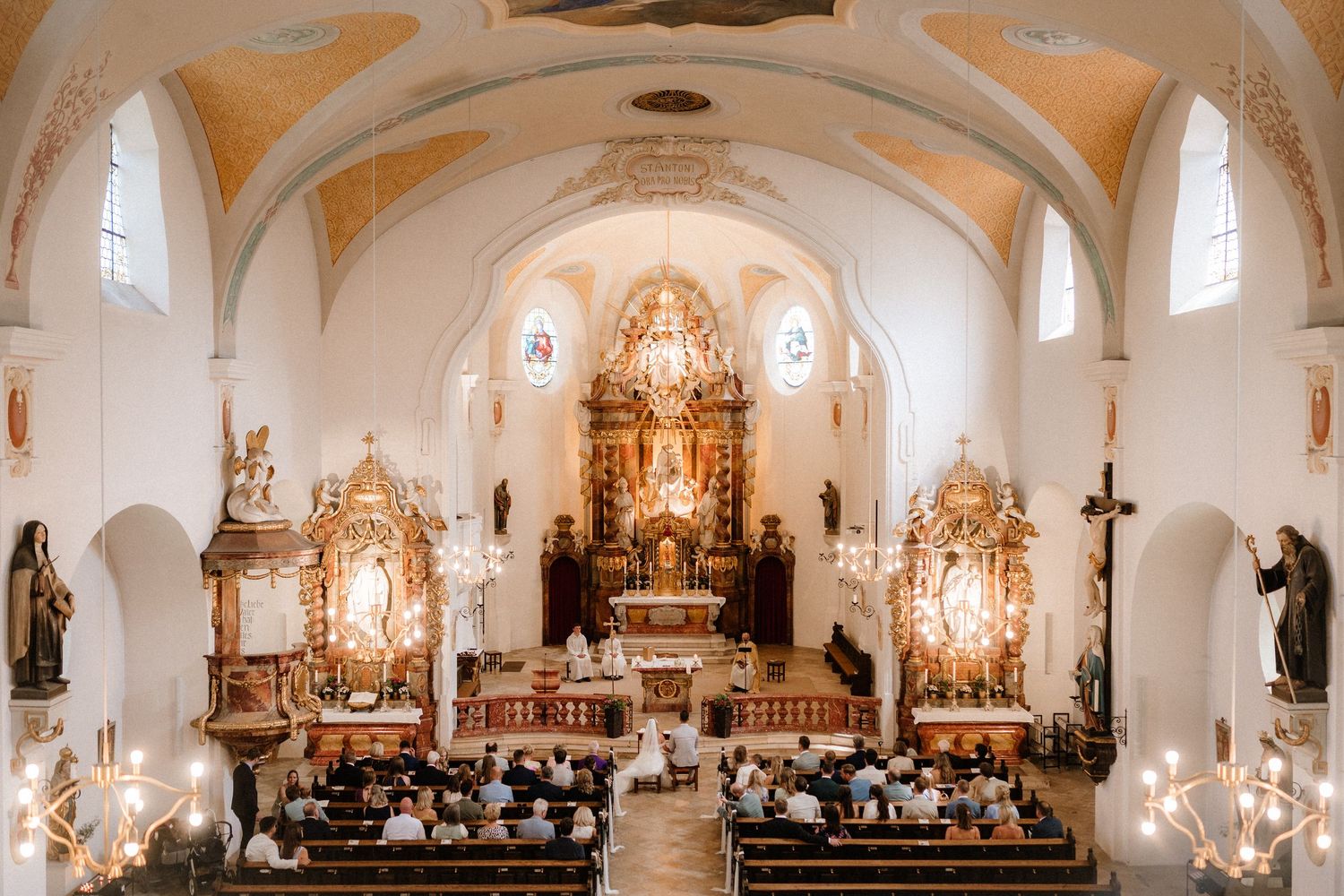Panoramic view of a traditional Catholic church interior with vaulted ceilings and ornate altar.