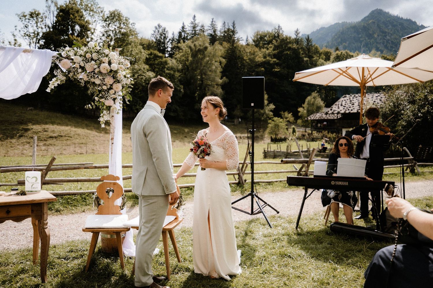 Outdoor wedding ceremony with mountain views and white umbrellas.
