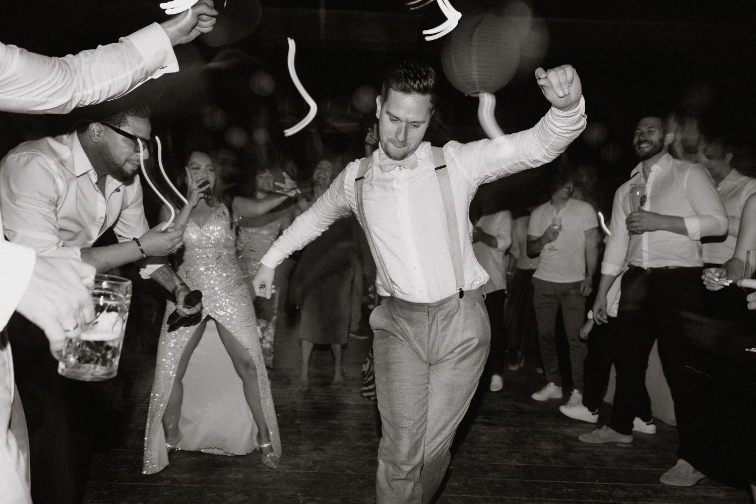 Black and white shot capturing dancing movements at a lively indoor celebration.