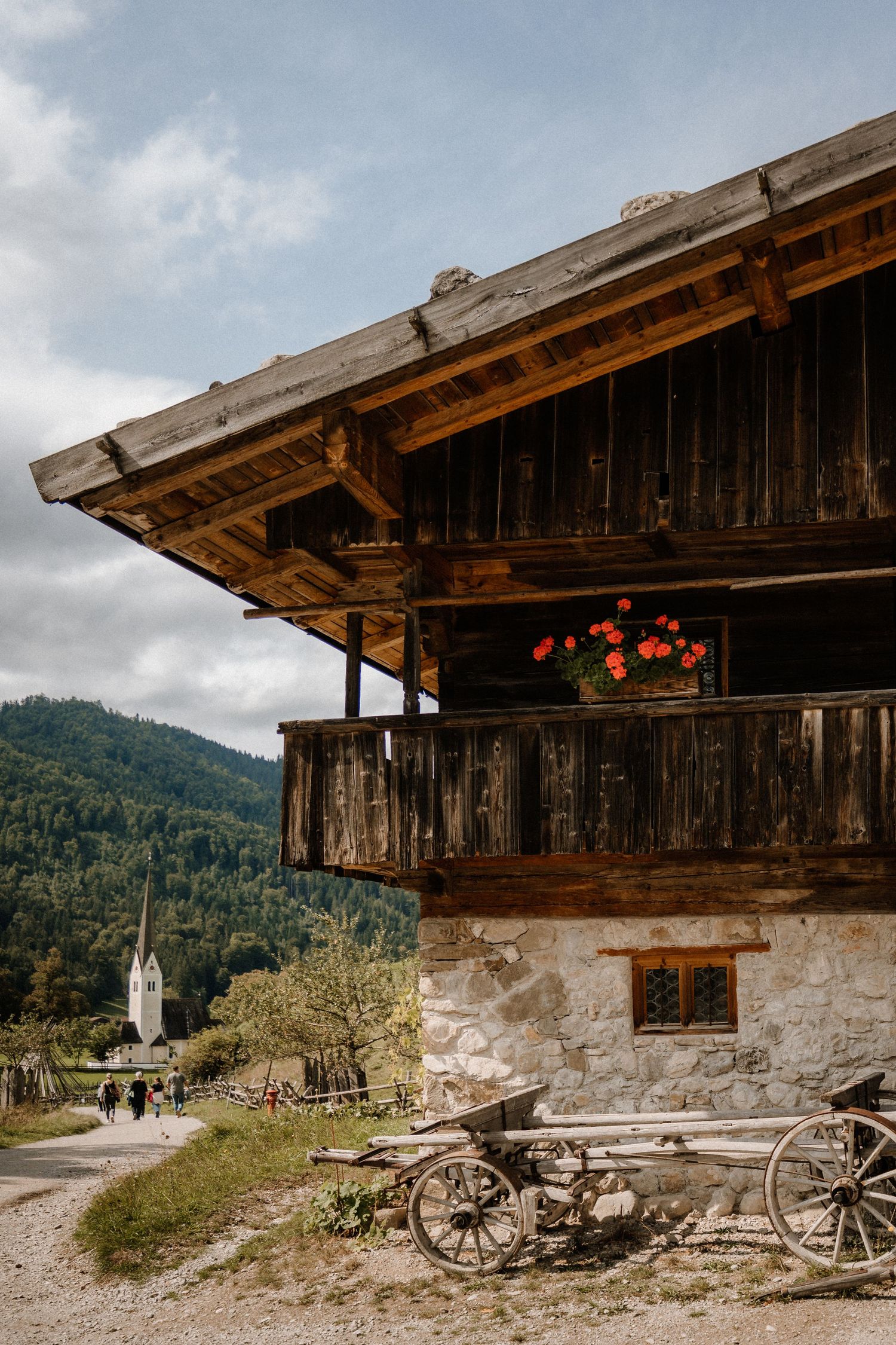A weathered rustic cabin with stone foundation and wooden details in a mountain setting.