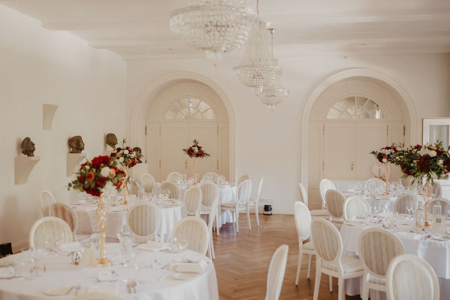 Wedding reception venue with white tables, elegant chairs and romantic lighting.