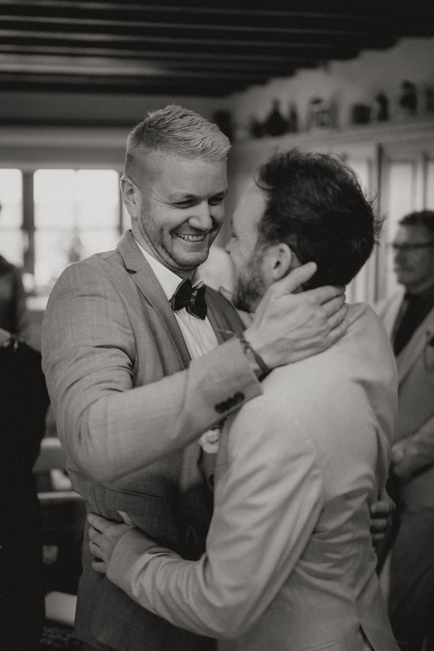 Black and white capture of two wedding guests sharing an emotional moment during celebrations.