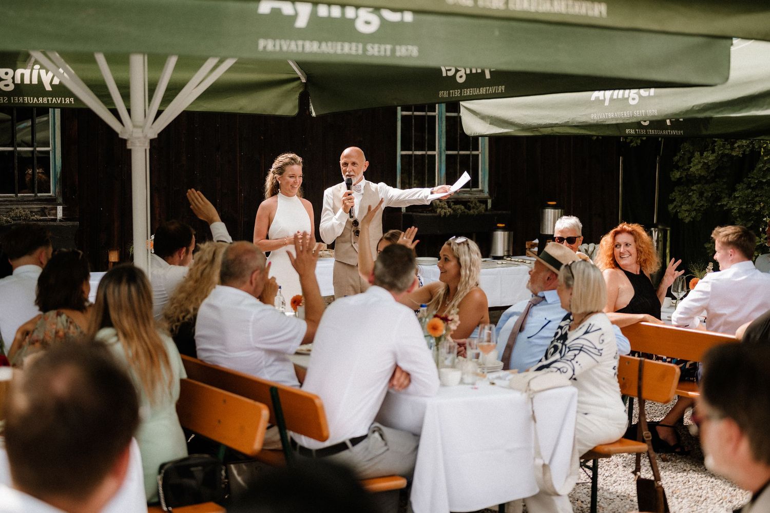 Guests enjoying a celebration at outdoor tables under white canopy tents.