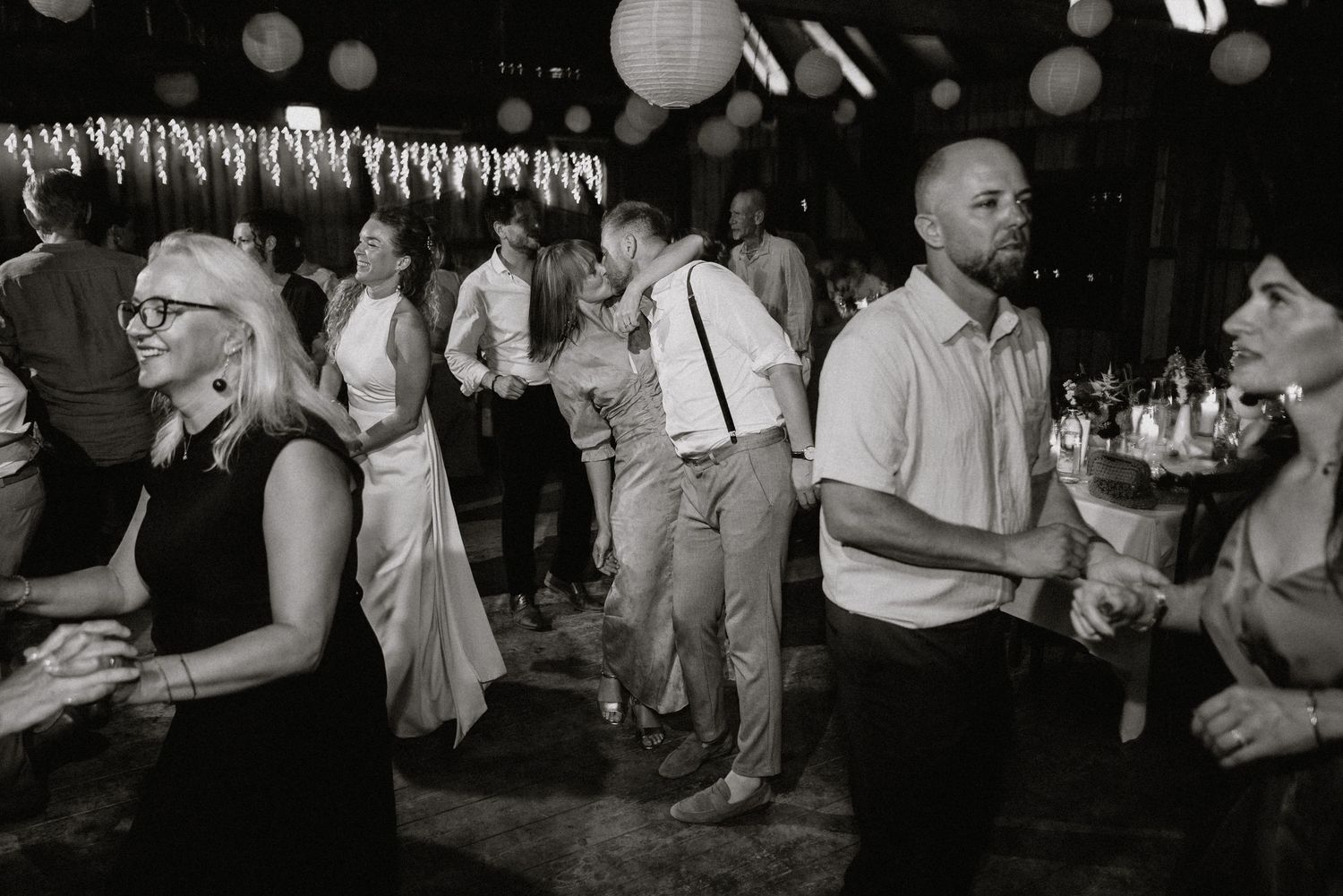 Black and white photo of wedding reception guests dancing and celebrating.