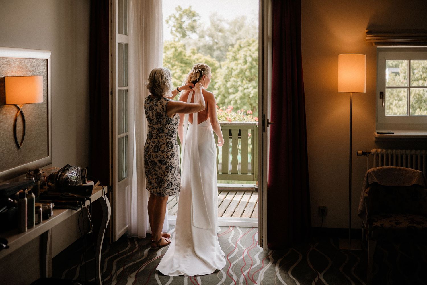 Wedding dress hanging in window frame with natural daylight streaming through.