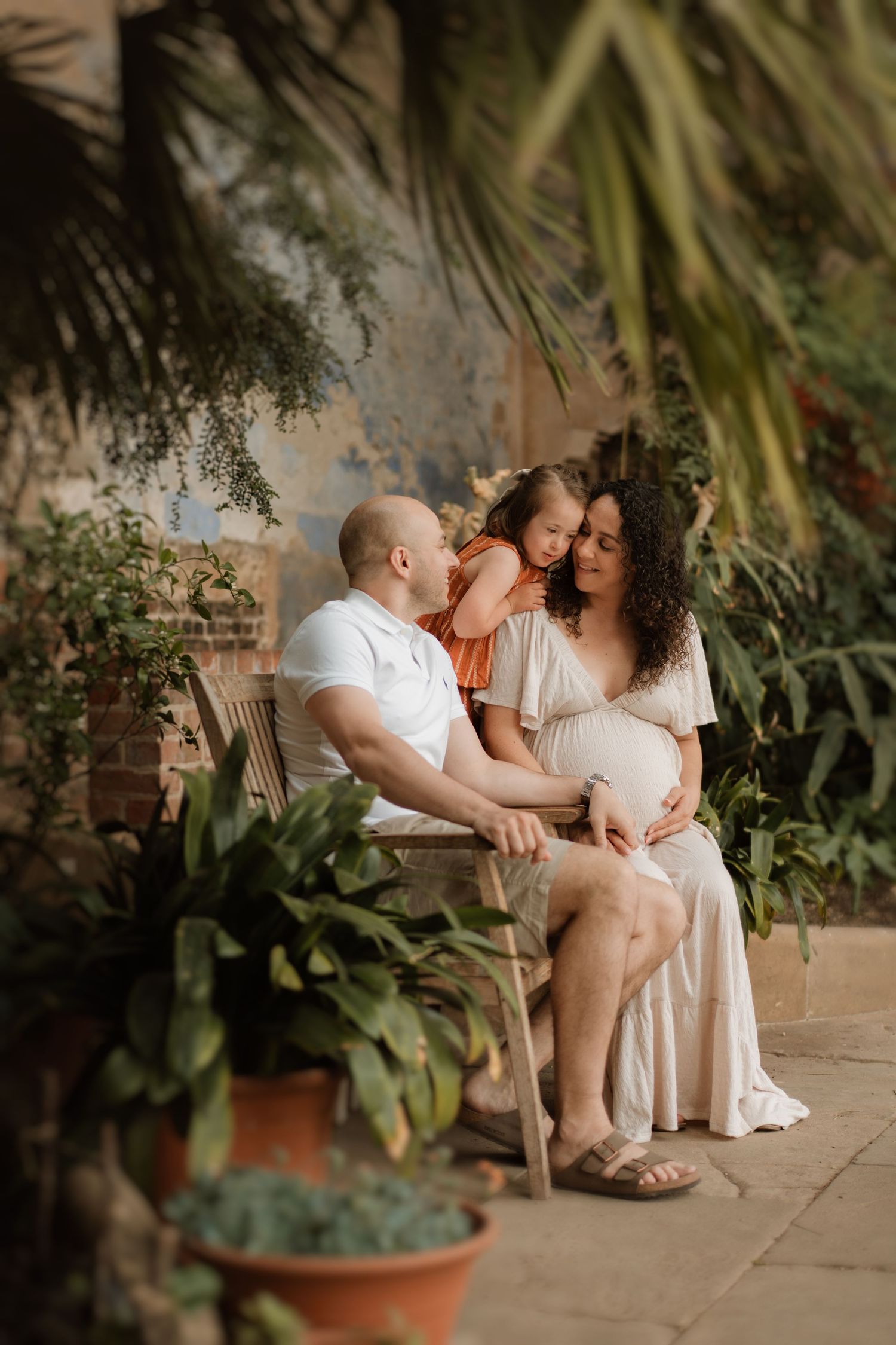a maternity photoshoot scene with mum, older daughter and dad, enjoing their time together and laughing