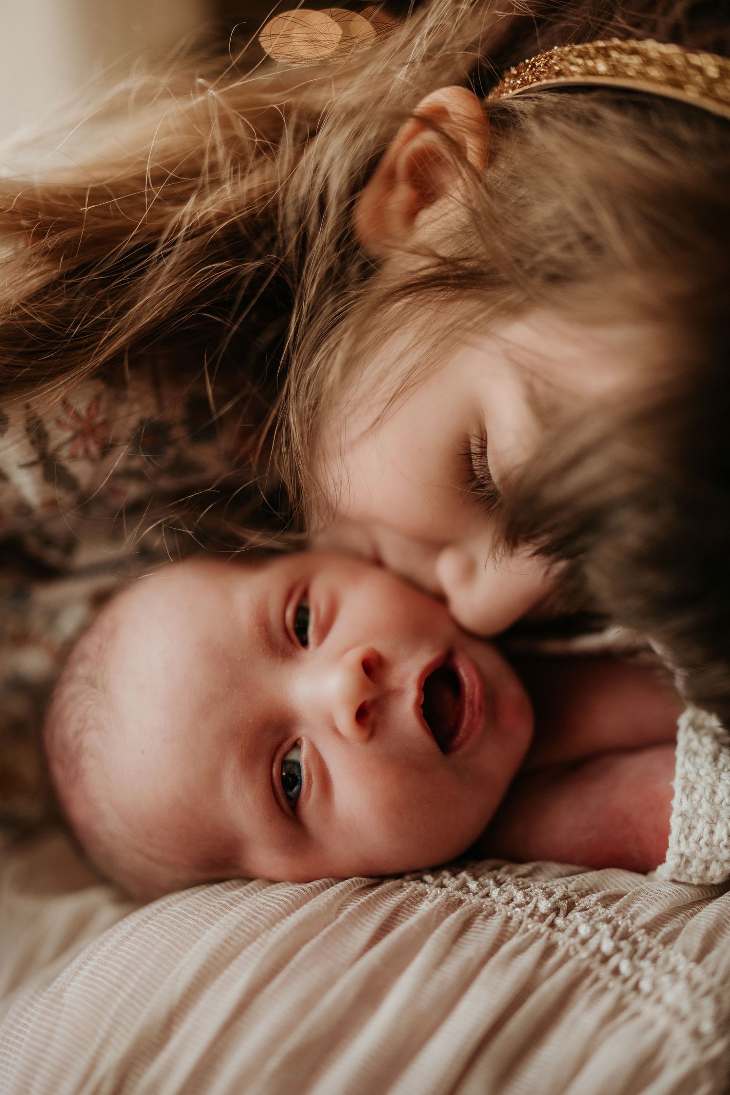 Older sibling cuddling a newborn, a tender everyday moment documented during a natural lifestyle photoshoot in East Midlands