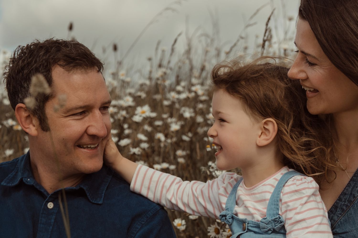 Family smiles together among wildflowers during a relaxed outdoor storytelling photoshoot in the Midlands.