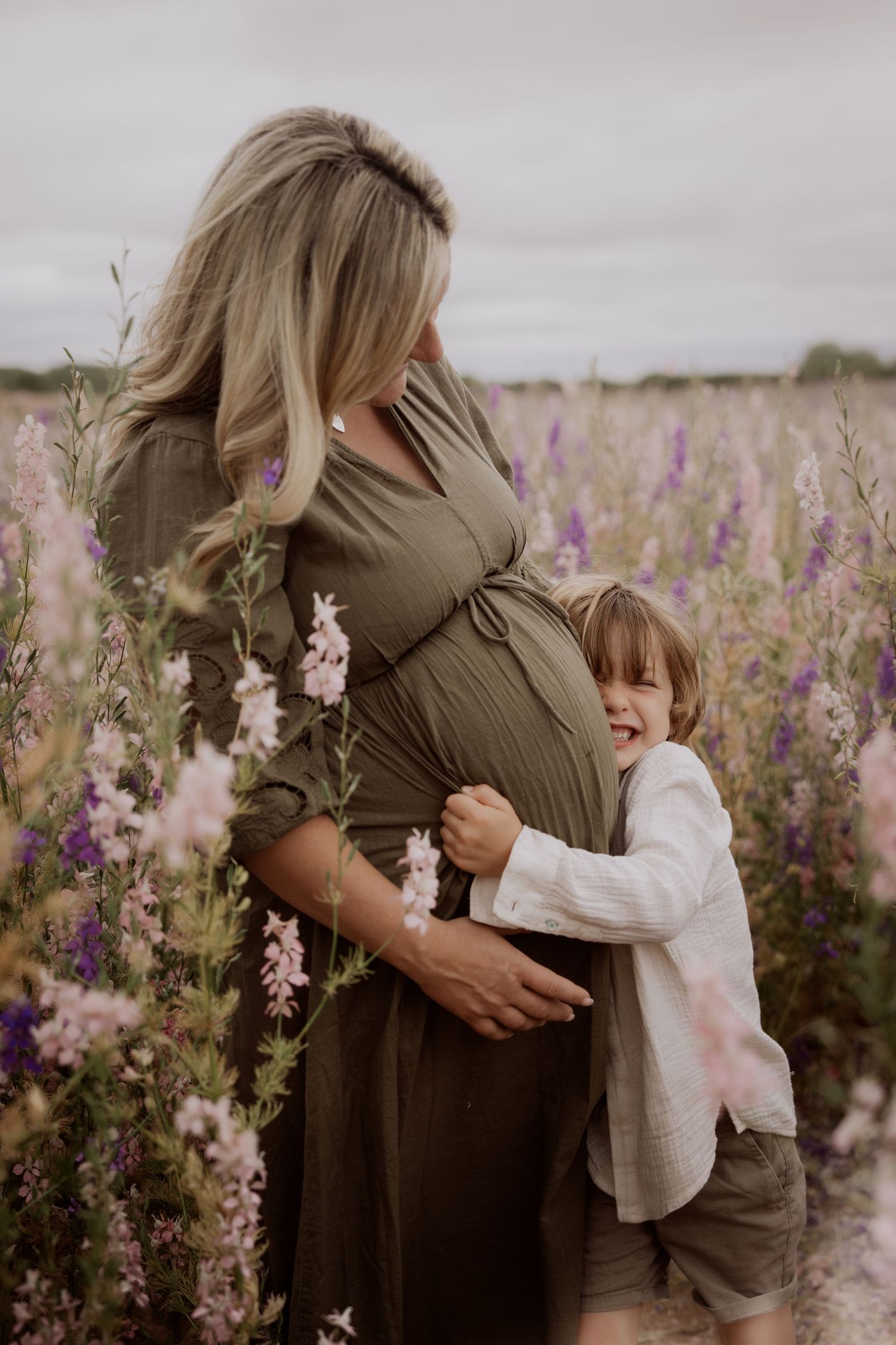 Pregnant mother embraced by her child in a meadow during an intimate documentary maternity photoshoot in confetti field