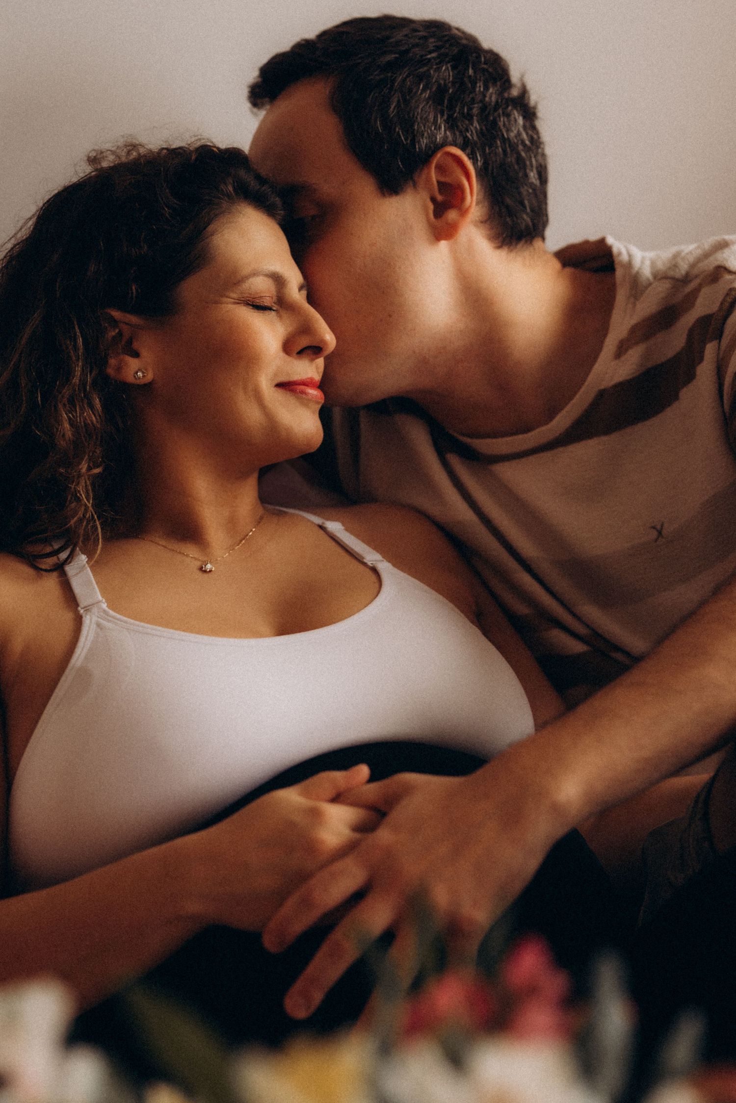 Couple sharing a tender moment during an intimate in-home lifestyle maternity and family session.
