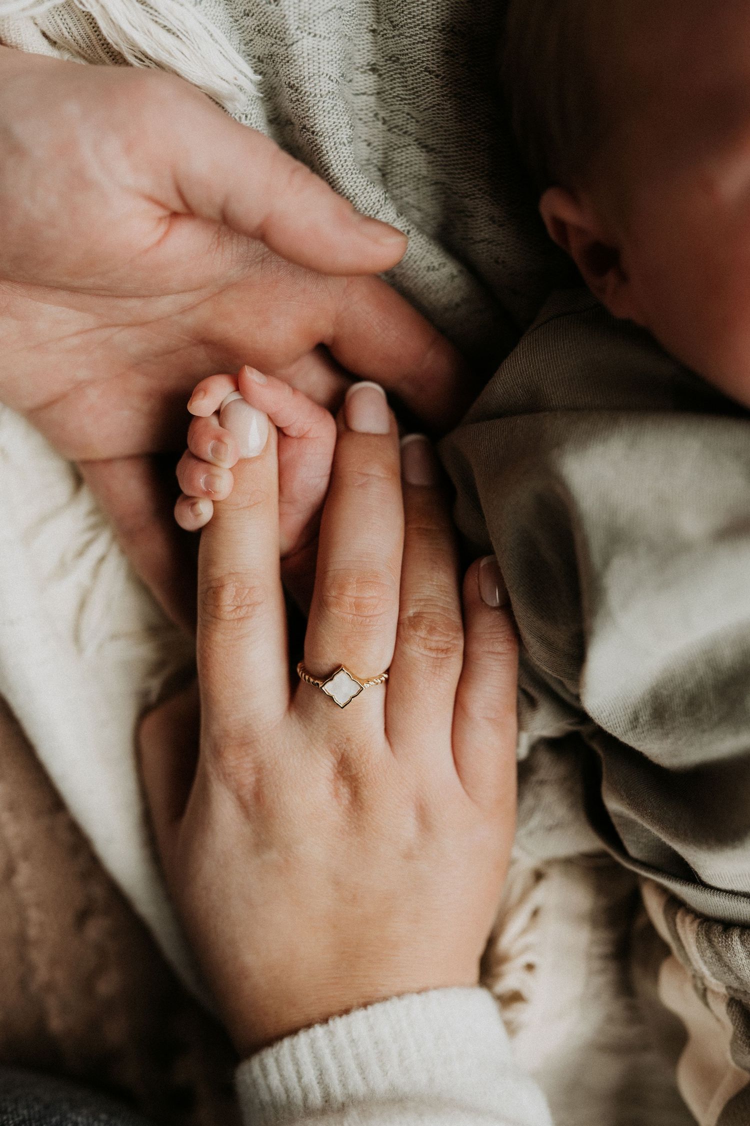 Parent holding a newborn’s hand during an intimate in-home lifestyle newborn photography session.