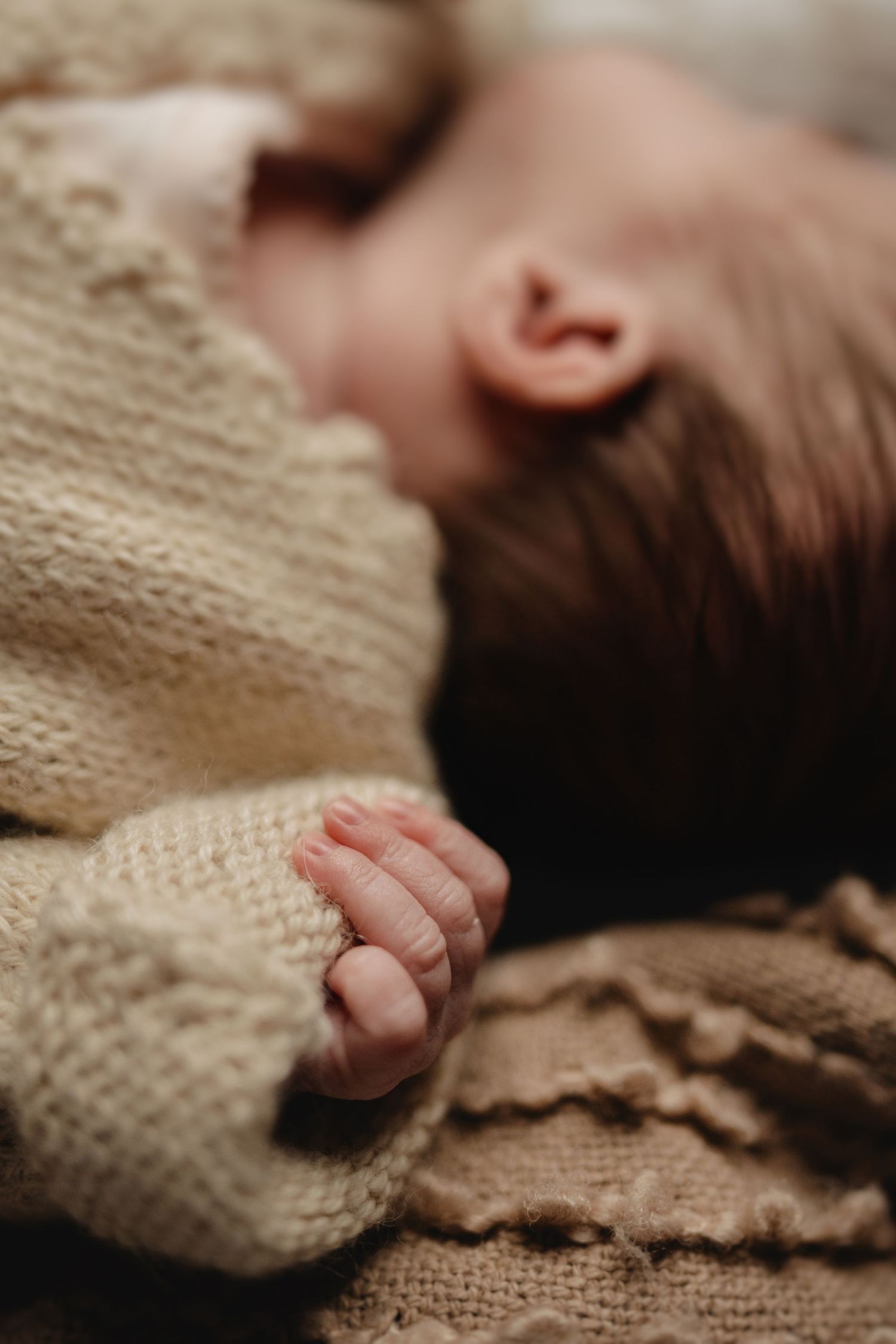 Newborn sleeps peacefully in a knitted vest during an intimate at-home photoshoot in Hugglescote
