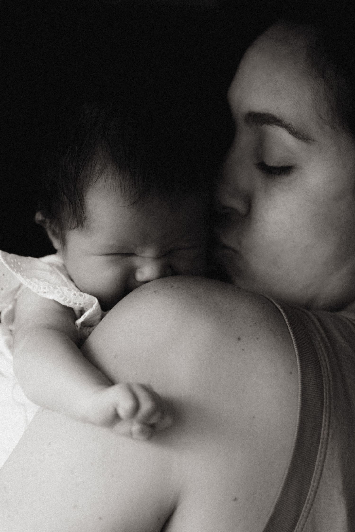 Parent comforting a newborn on their shoulder during a natural light lifestyle newborn photography session.