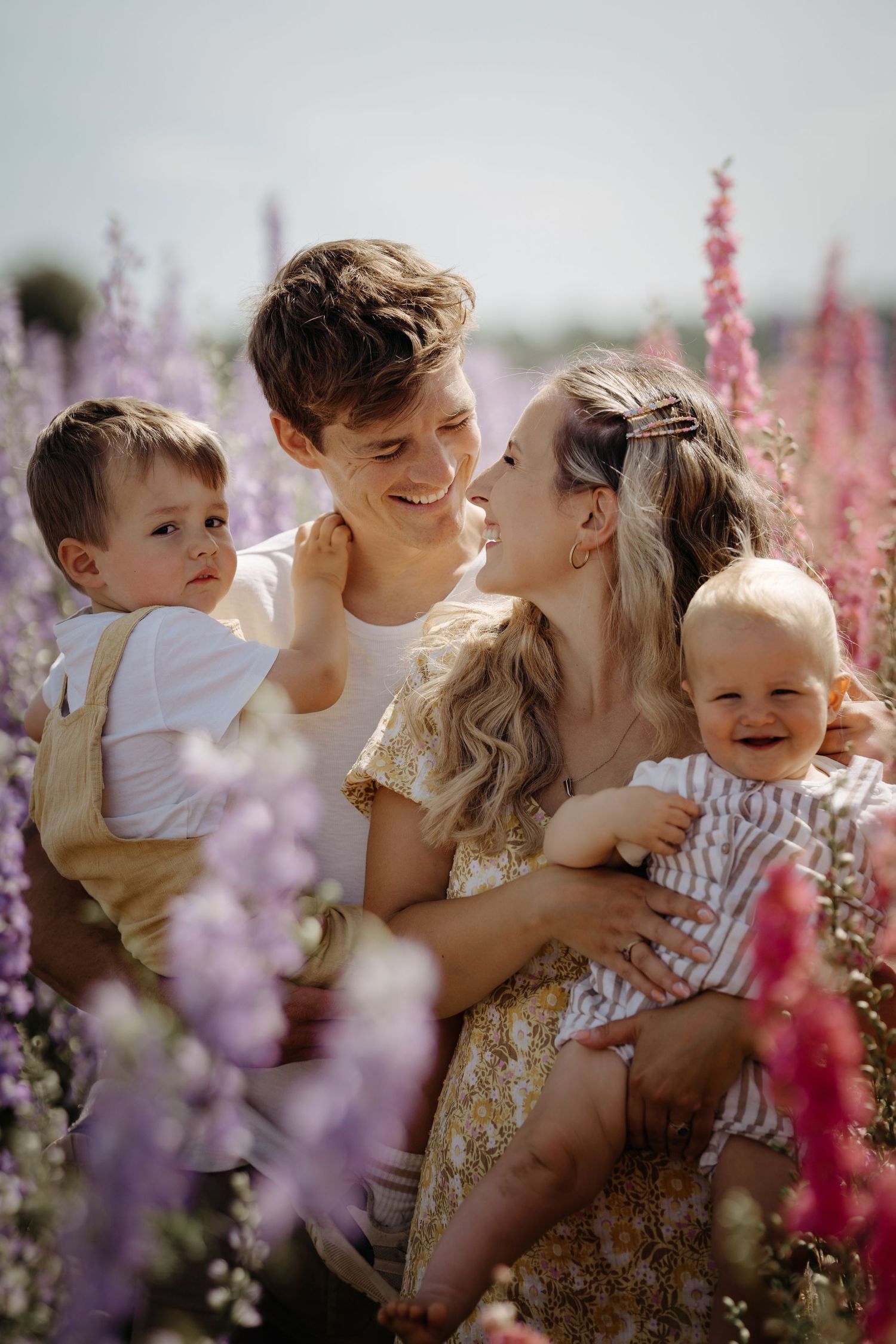 Family with children sitting together in a flower field, captured in warm light during a relaxed outdoor lifestyle photography session