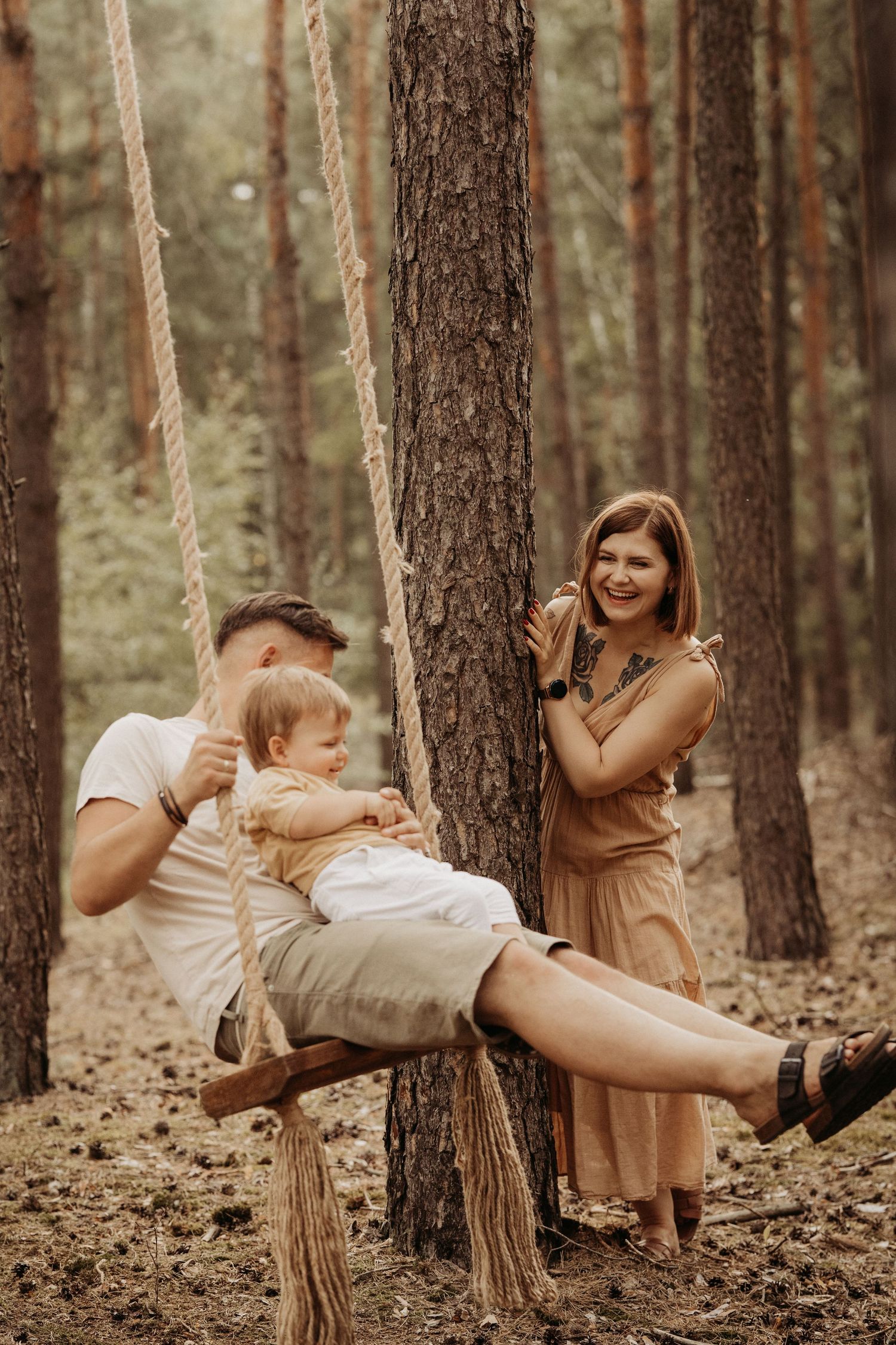 Family sharing a quiet moment on a rope swing in the forest, photographed during a documentary-style family photoshoot in the Midlands
