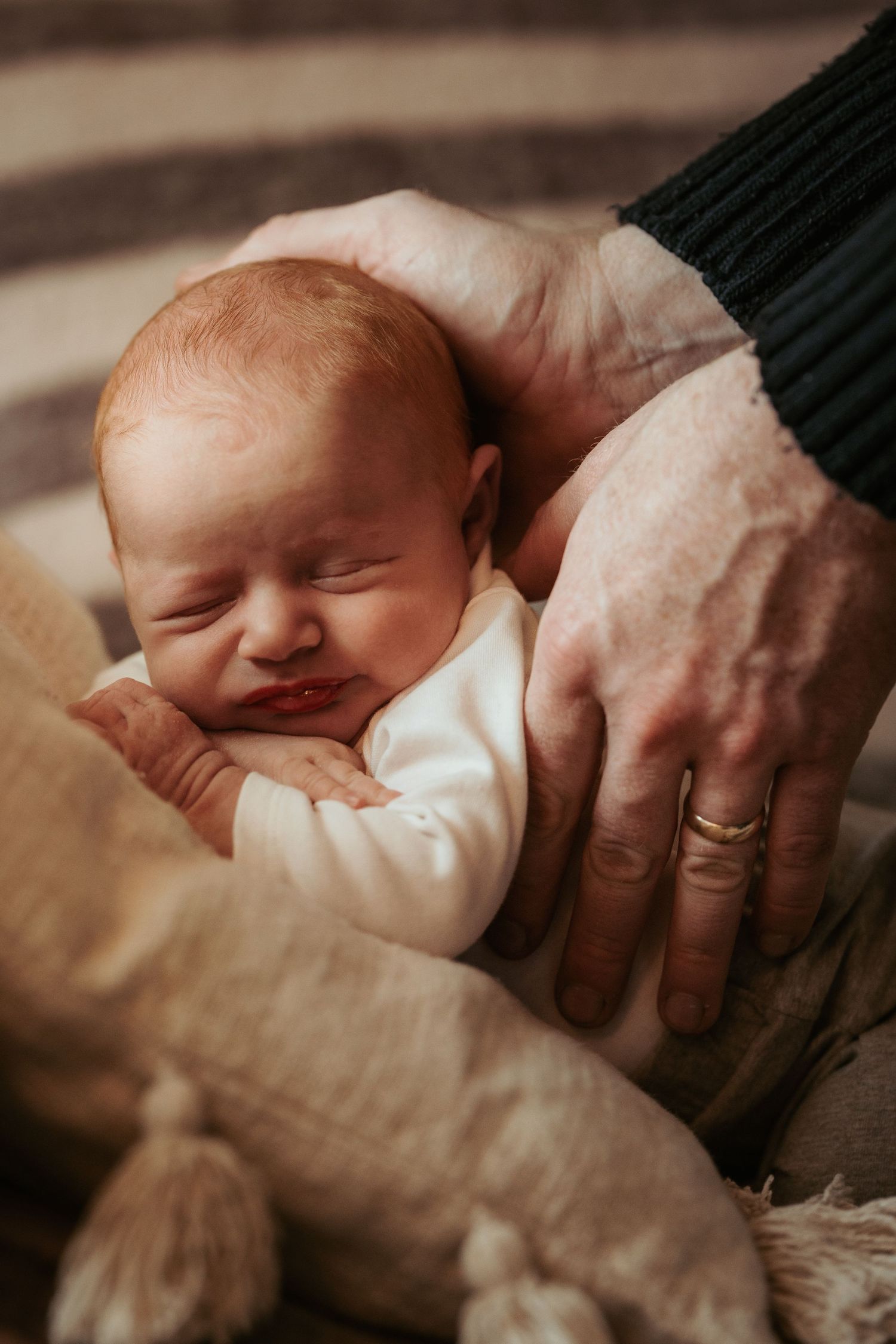 Newborn resting in adult hands during a quiet storytelling newborn photoshoot in natural light.