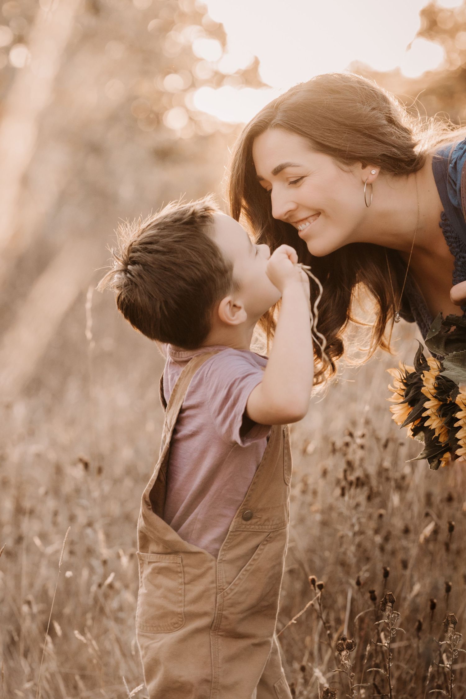 Mother and son share a sweet moment surrounded by wildflowers during a warm evening photoshoot.