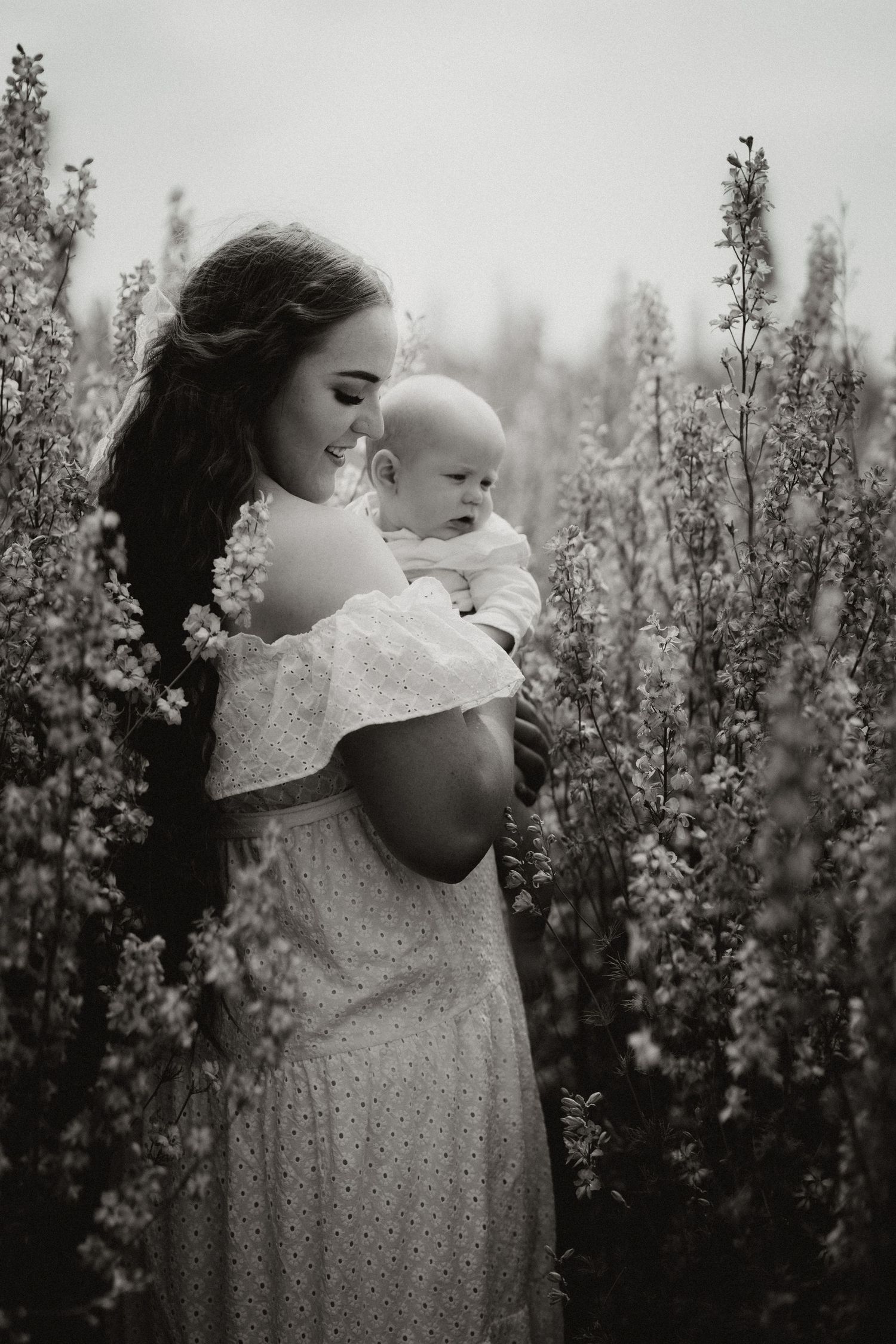 Mother holding her newborn in a flower field during an outdoor documentary motherhood photography session in Confetti Field